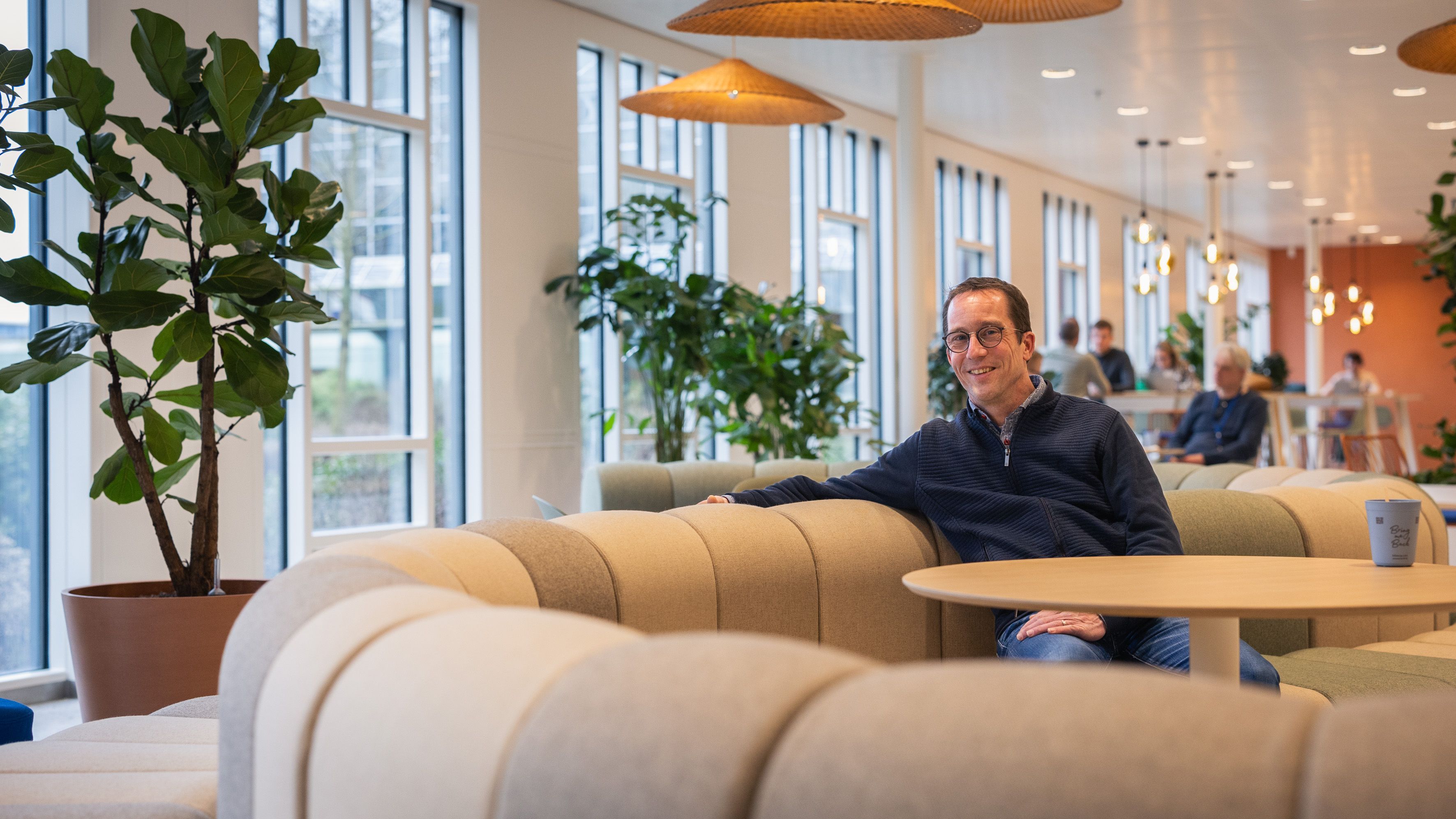 Man zit op een bank en kijkt in de camera