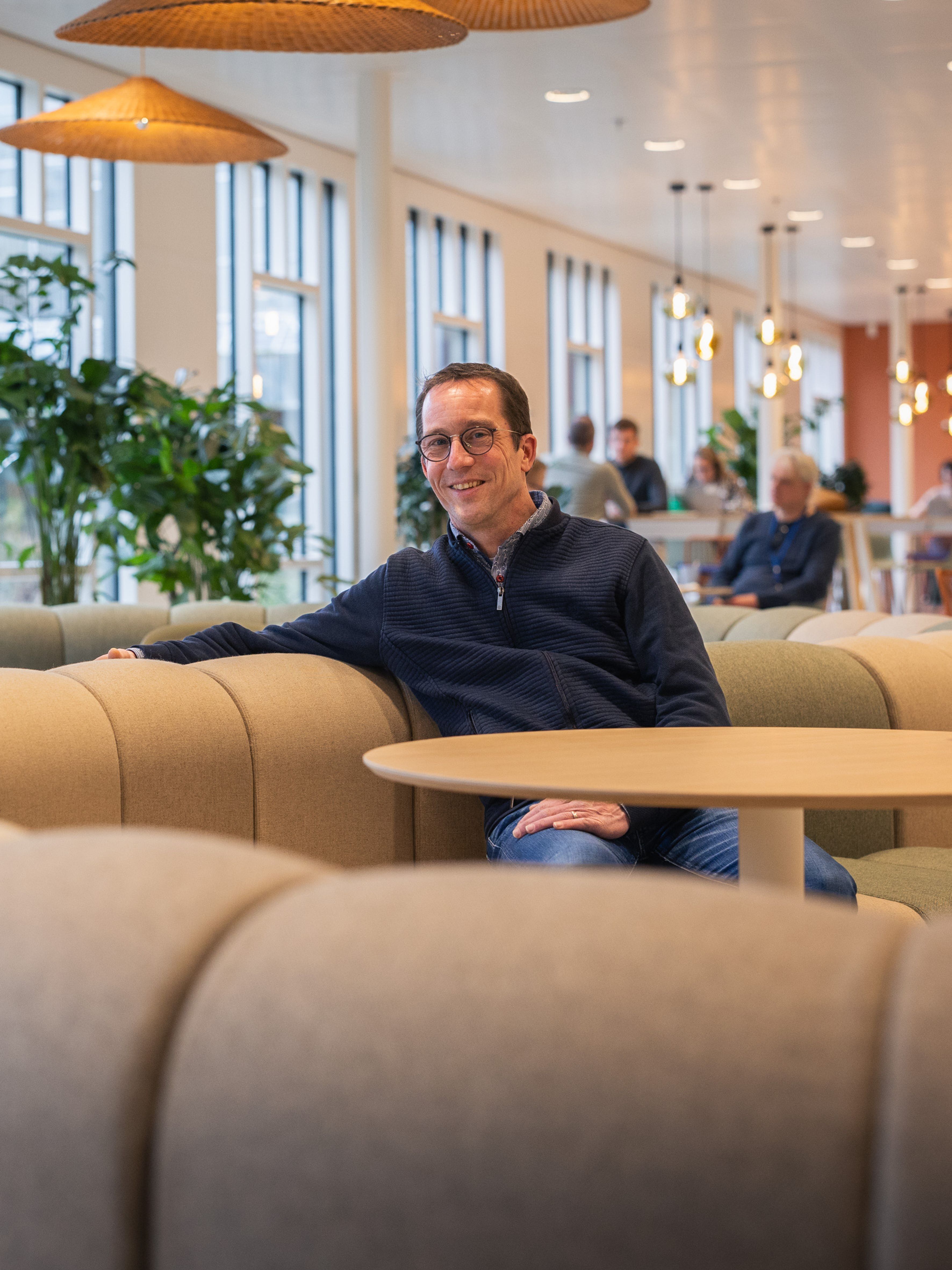 Man zit op een bank en kijkt in de camera