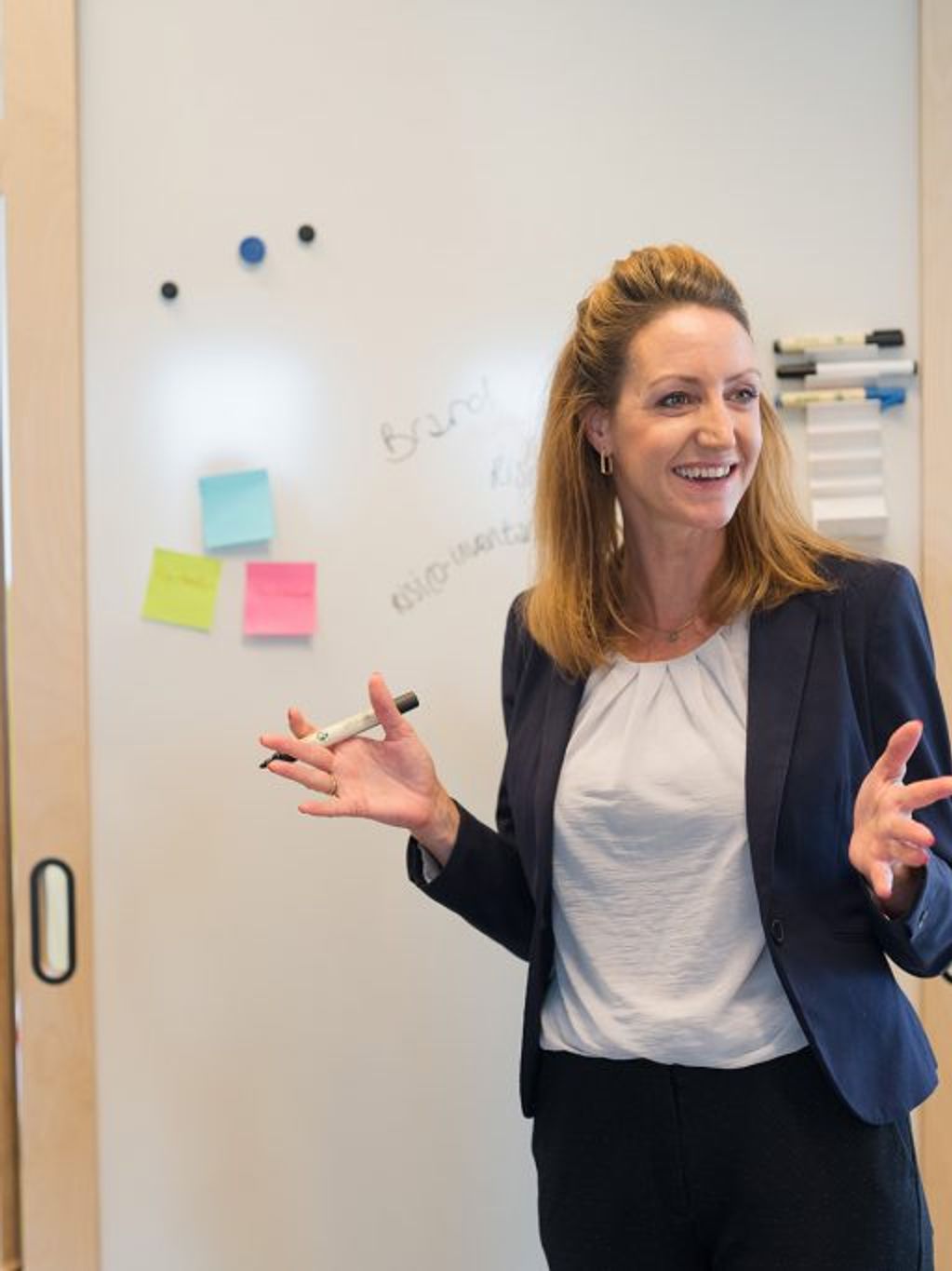 woman in conversation with two colleagues in front of a whiteboard