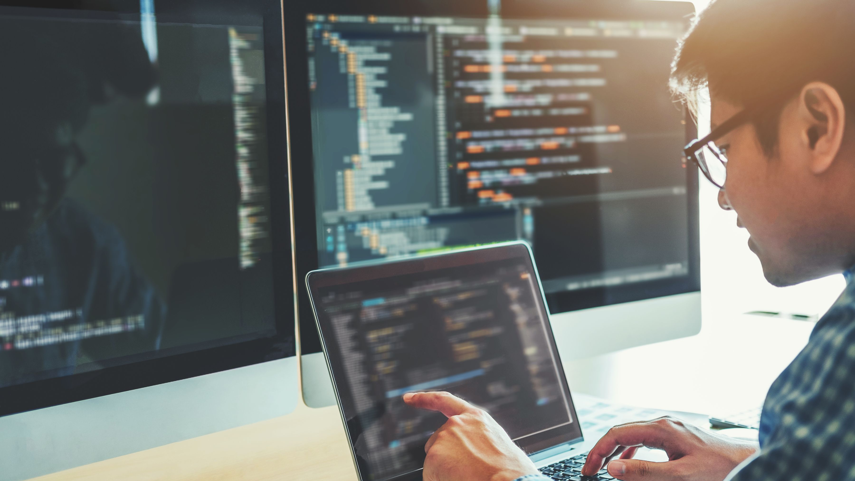 Jongen met drie computerschermen checkt data