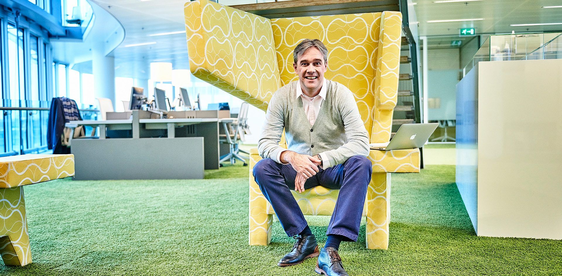 Menno glimlacht en zit in gele stoel