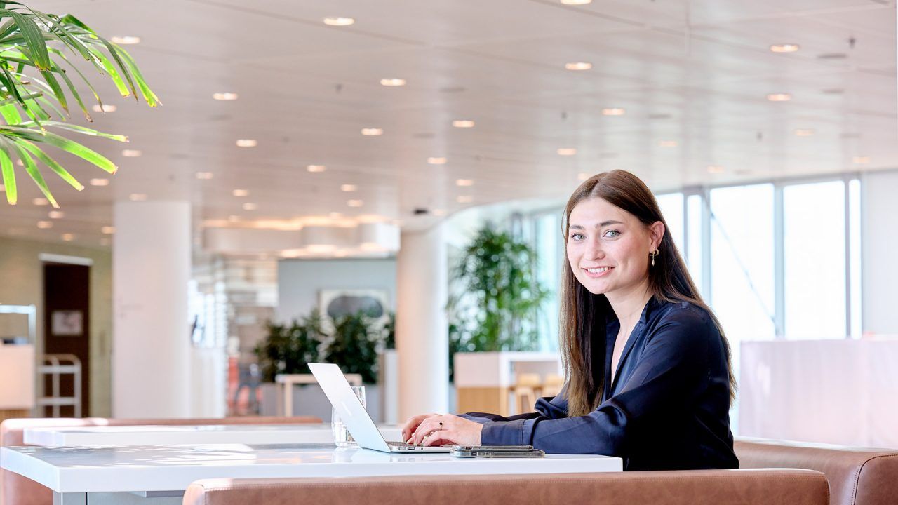 Young women is sitting behind laptop and looking into the camera