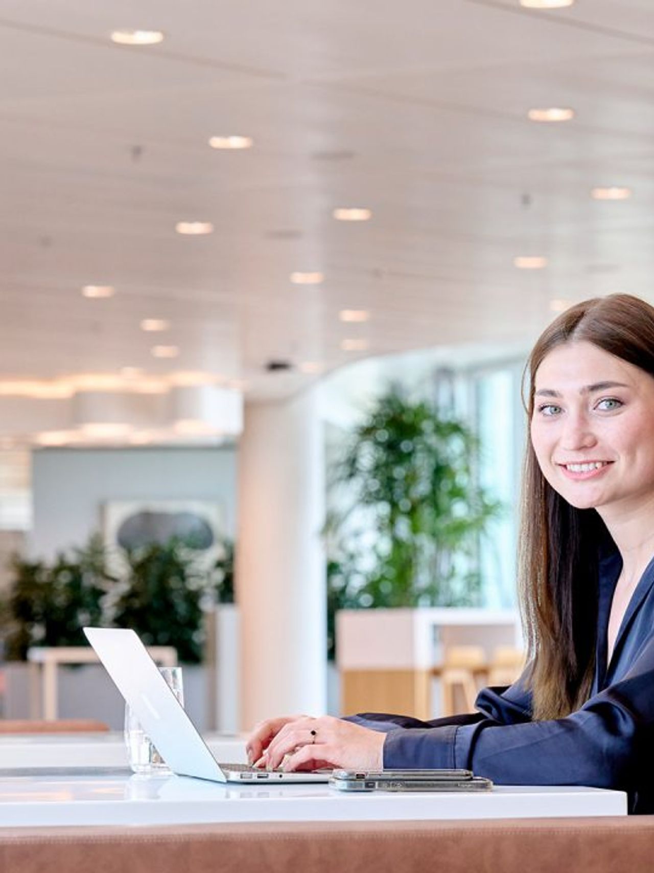 Young women is sitting behind laptop and looking into the camera