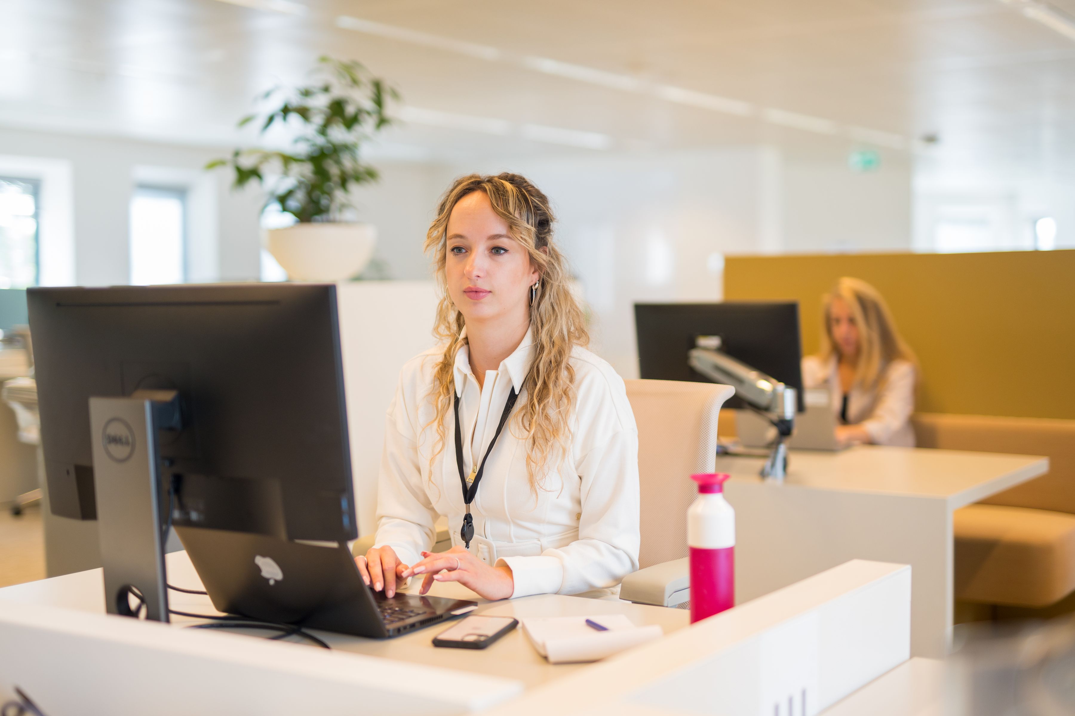 Celeste, CDD analist, werkend achter laptop en grote monitor.