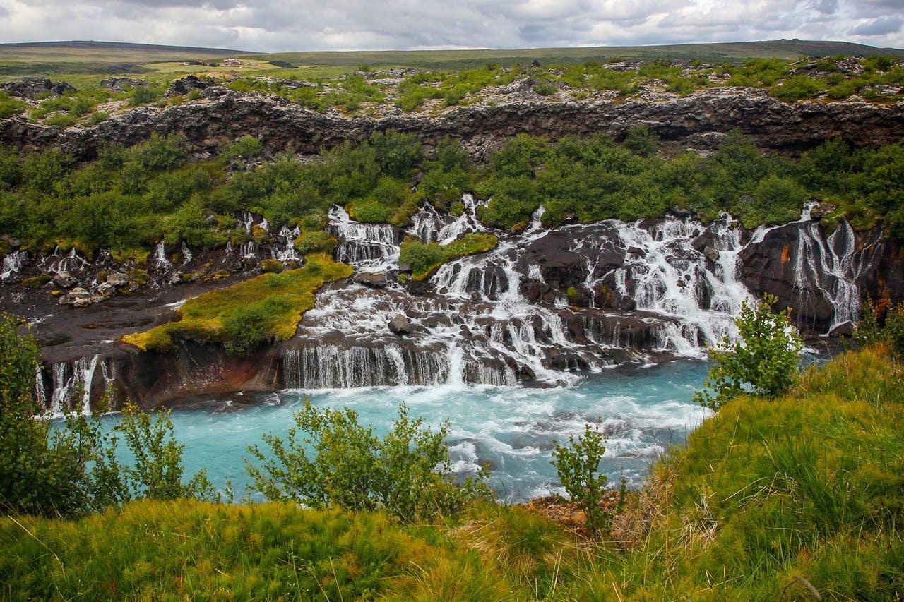 Hraunfossar, Lava waterfalls, in Iceland: Multiple waterfalls that run from a lava field into a blue river