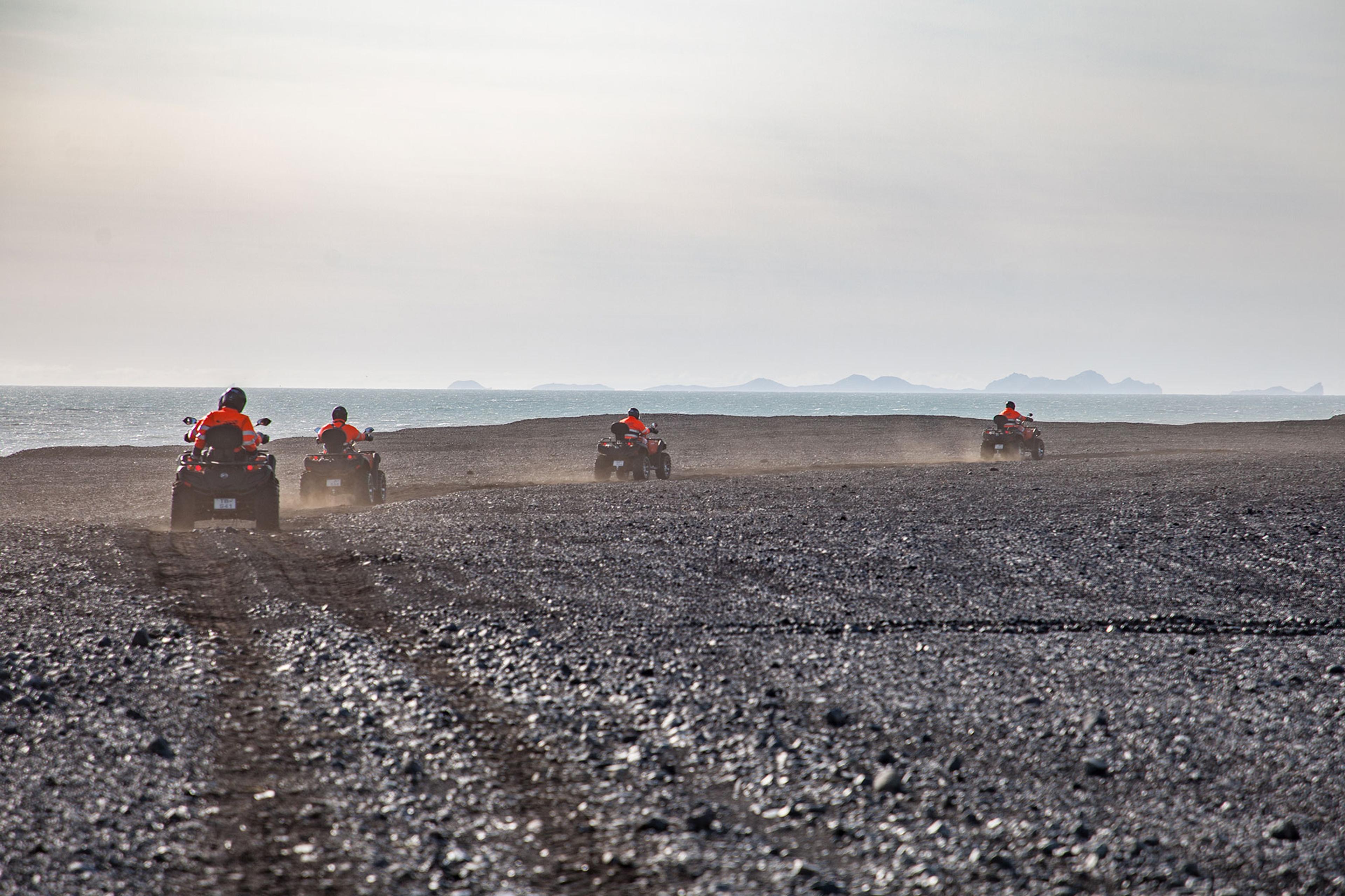 The wind blows the sand about as the ATV quad bike riders go wild on the black sand beach