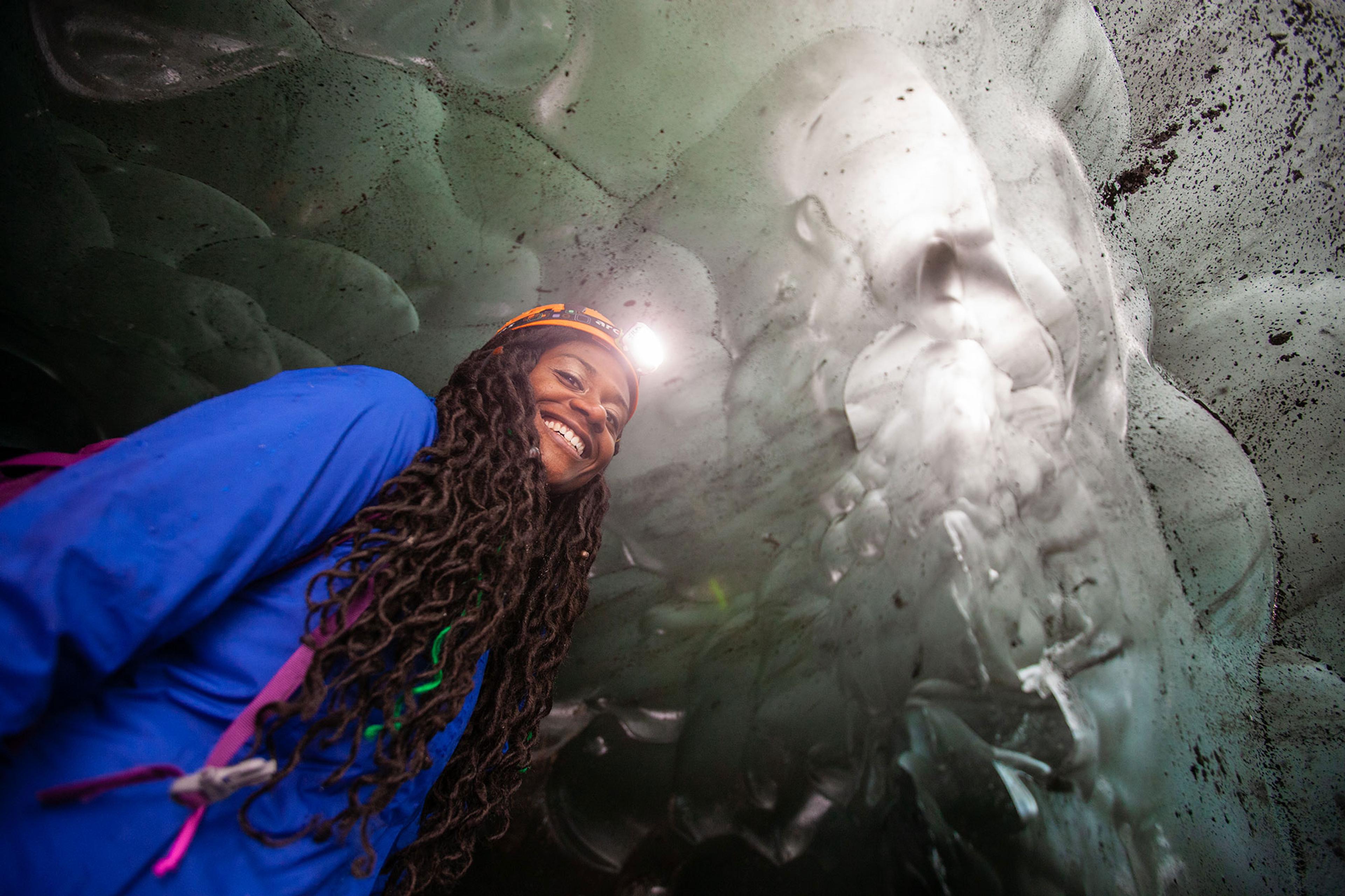 A woman with a head light inside an ice cave