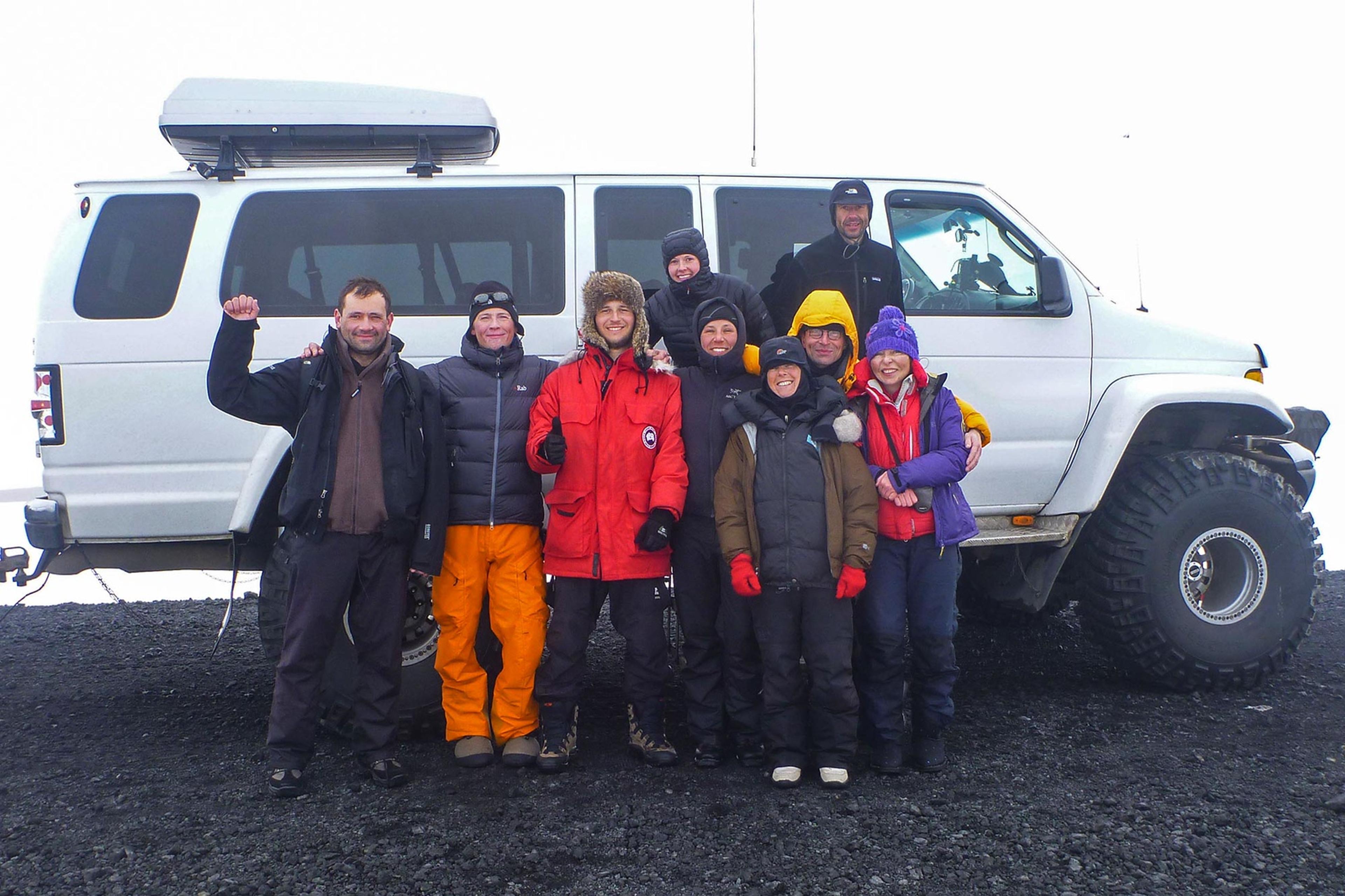 People standing in front of a super jeep picking them up after the expedition