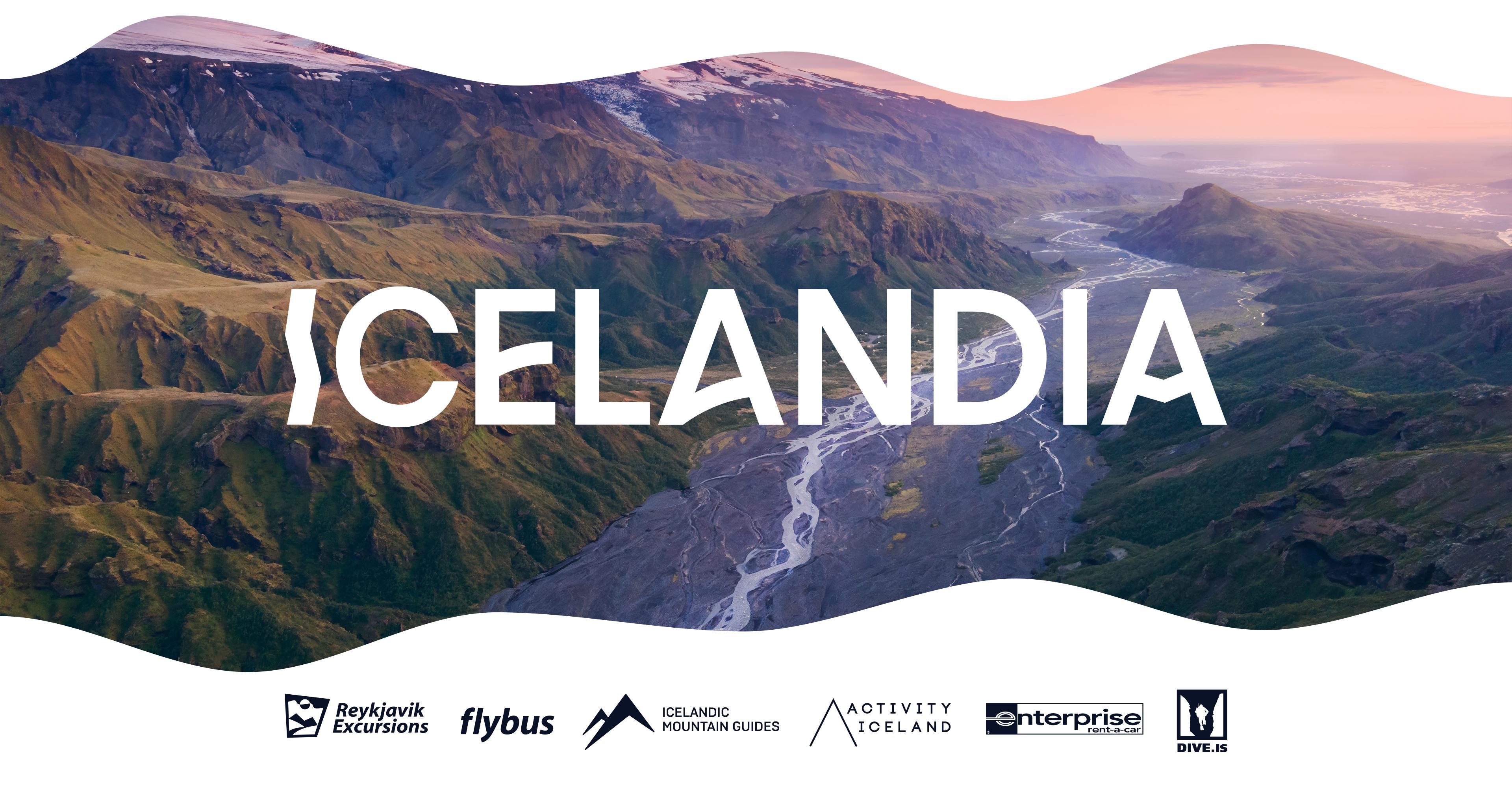 A scenic aerial view of an Icelandic mountain valley at sunset, featuring green ridges, a winding river, and snow-capped peaks in the distance. The word “ICELANDIA” is prominently displayed in bold white letters