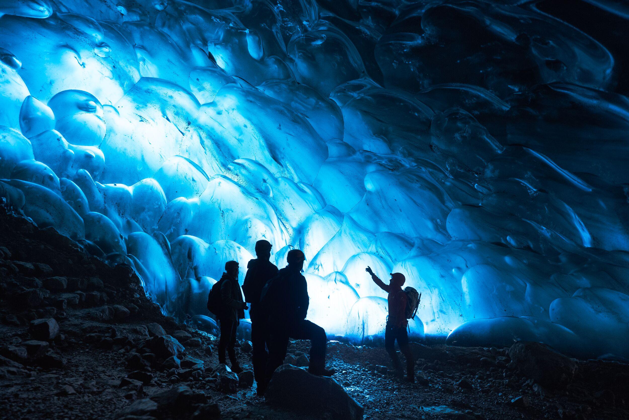 Three explorers and a guide stood inside a blue ice cave in Iceland