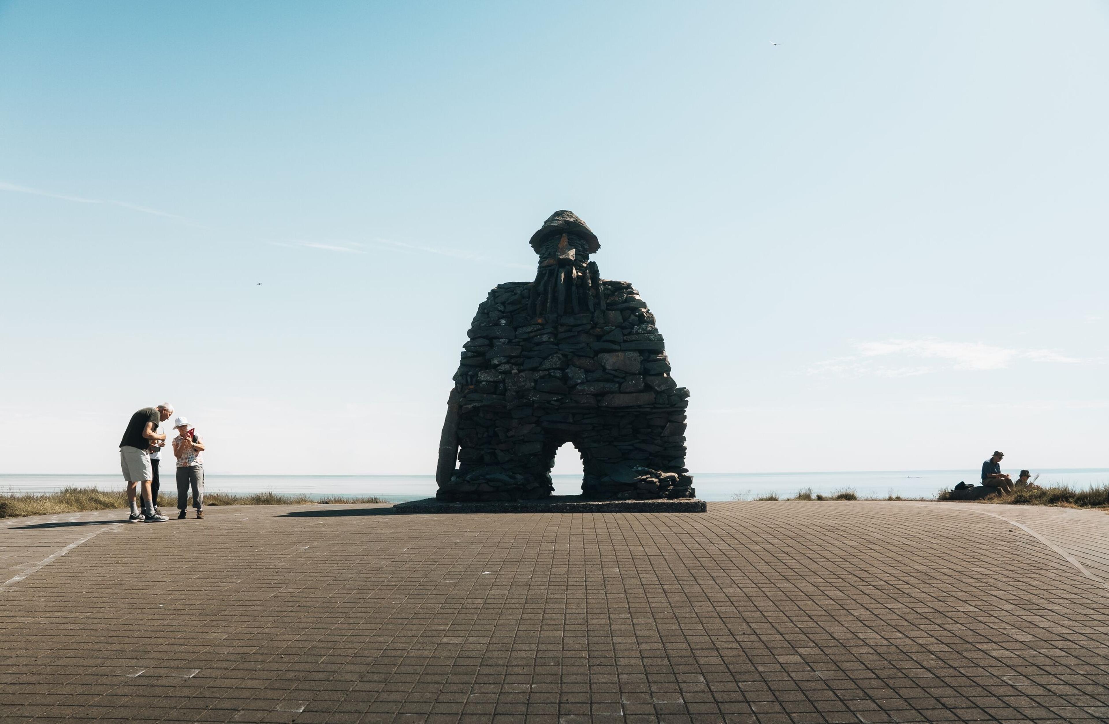 tourists standing by a statue of Thor