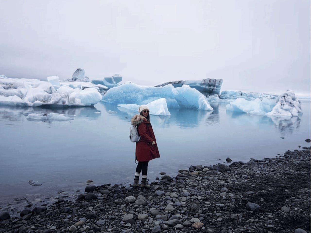 A woman with a strong red coat Game at the blue Glacier Lagoon