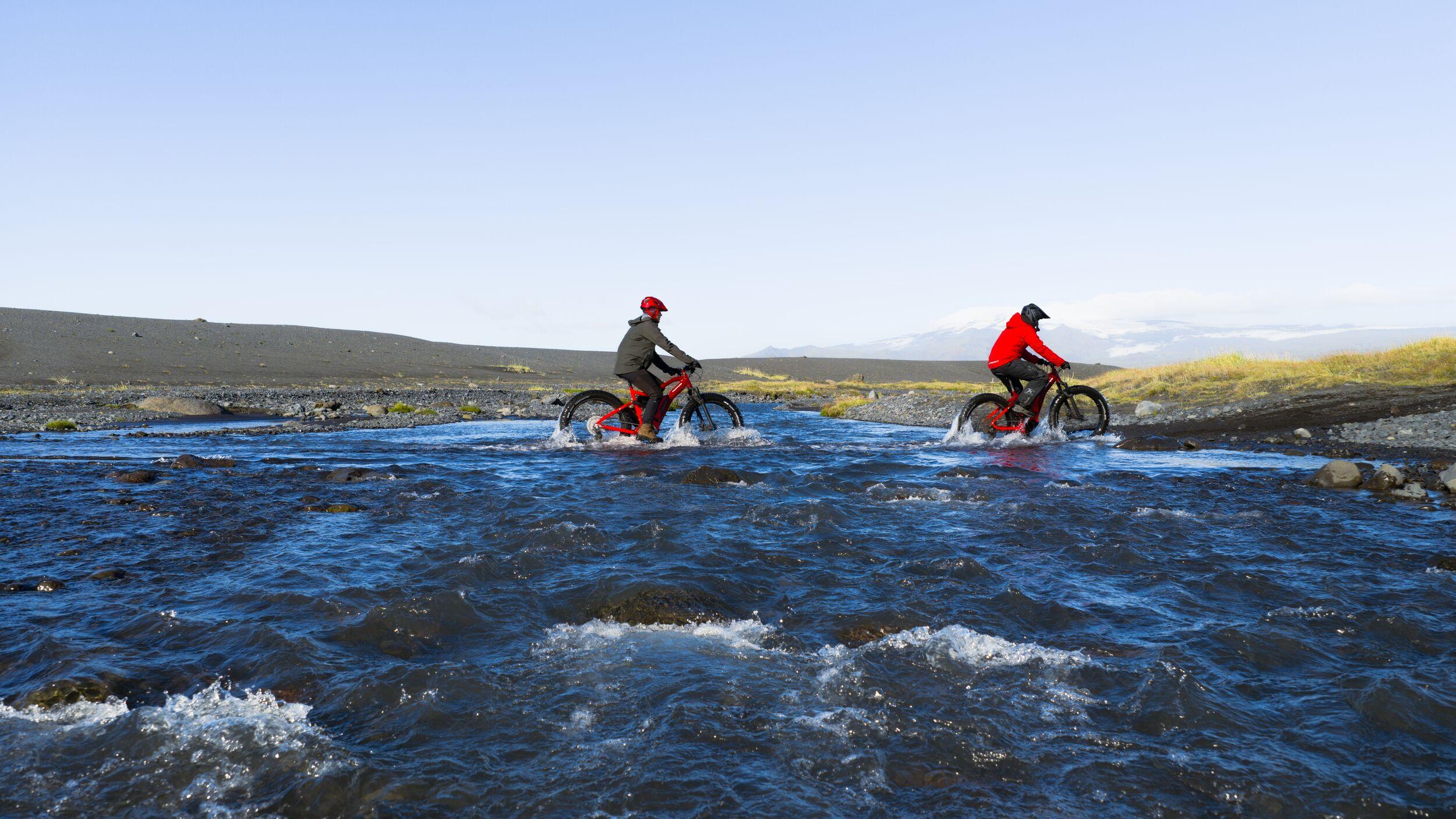 two people riding bikes over a river