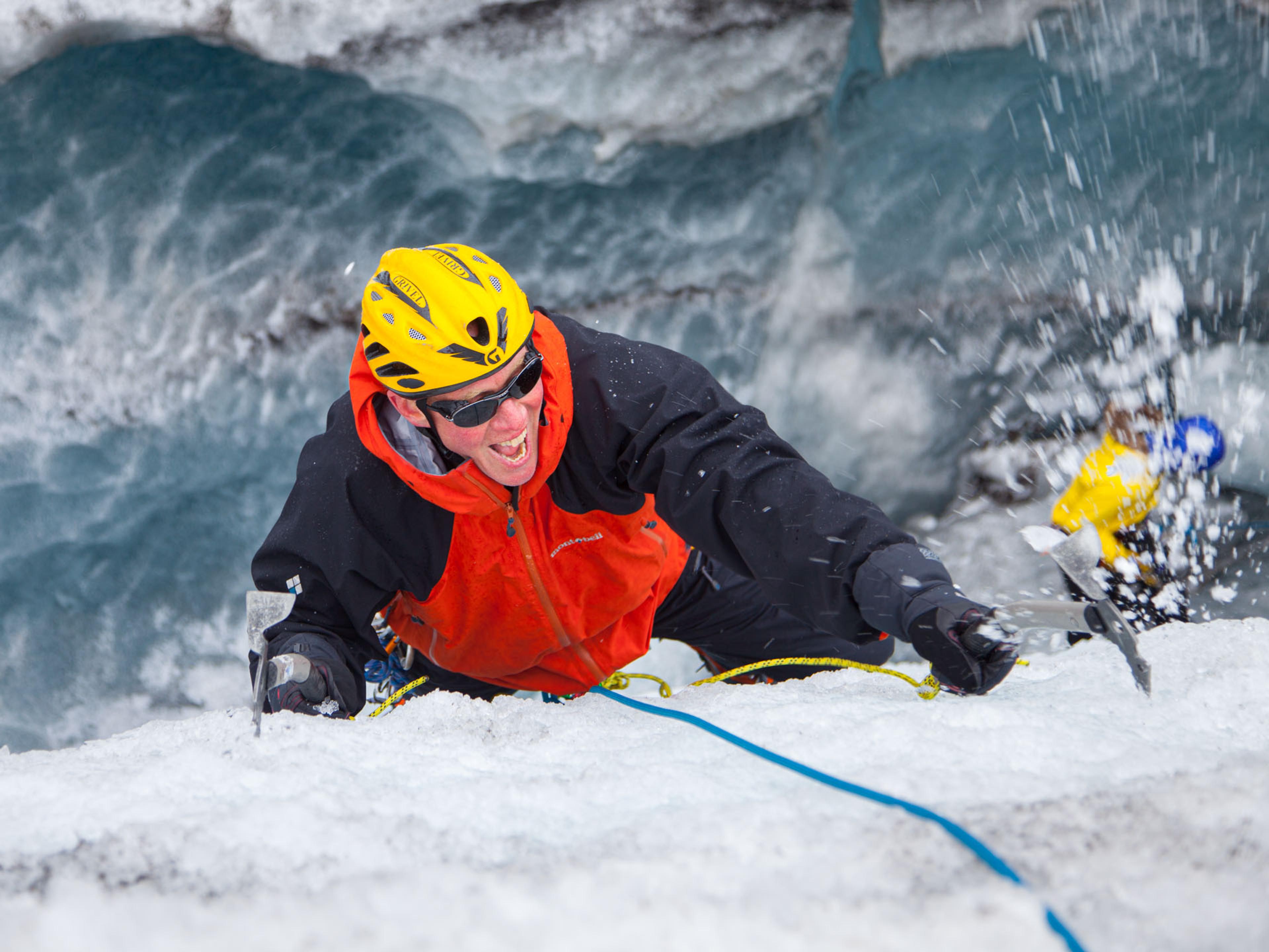 A man in a red jacket practicing ice climbing