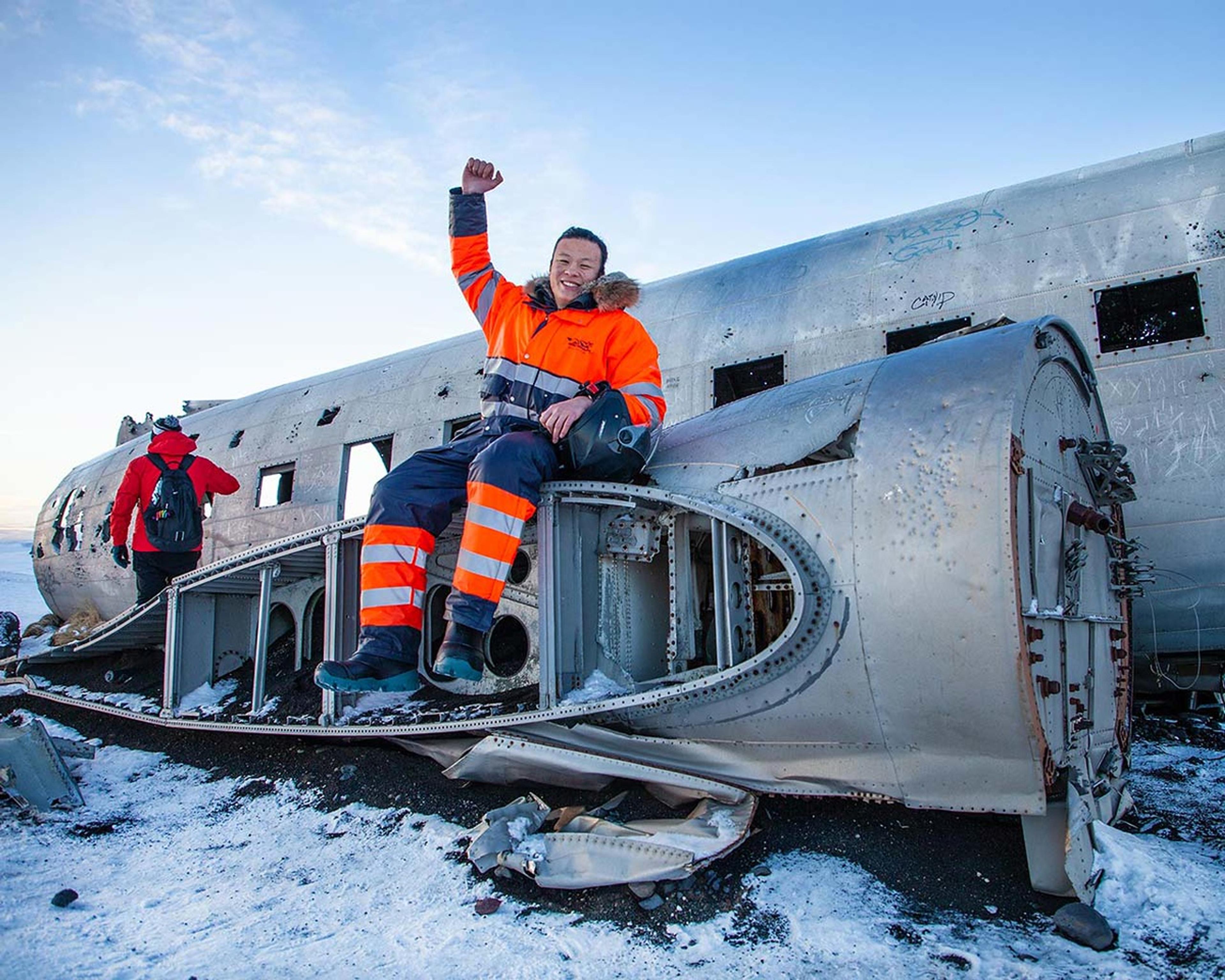 A man sitting on one fot eh engines of the Sólheimassandur old DC-3 plane wreck