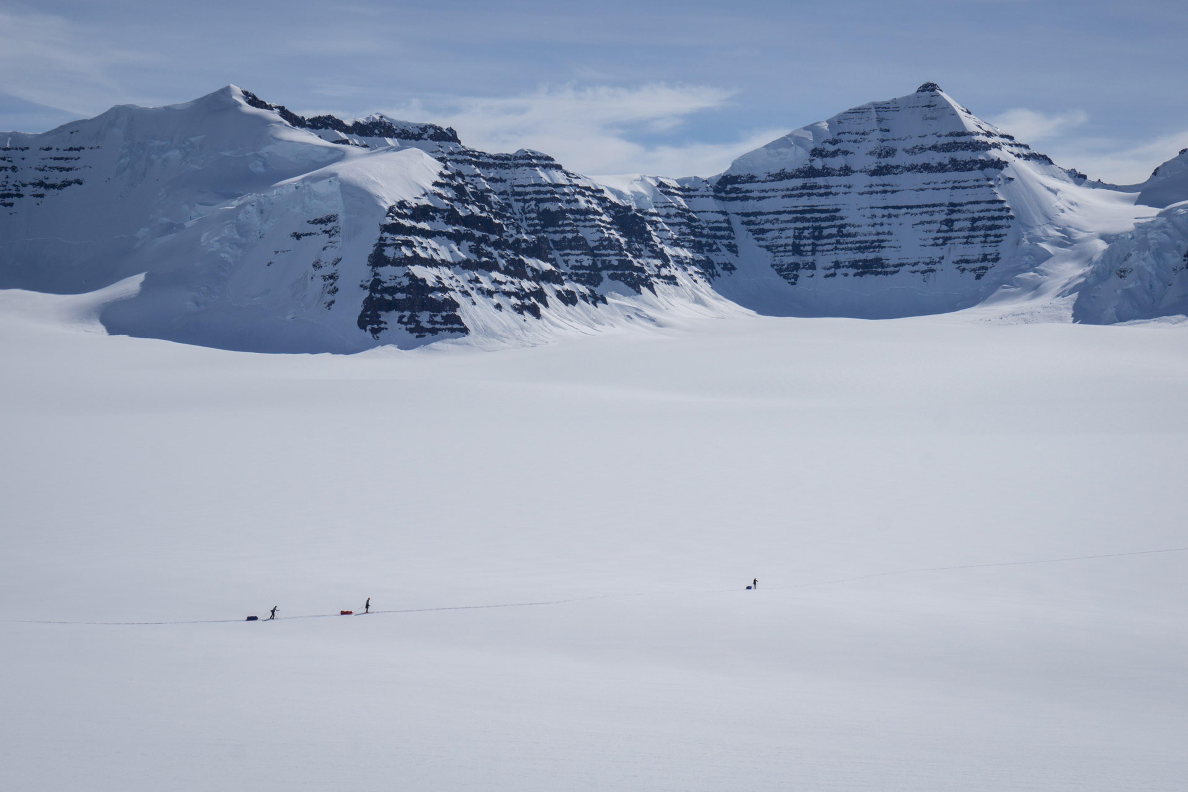 Skiers in the distance down on the flat glacier