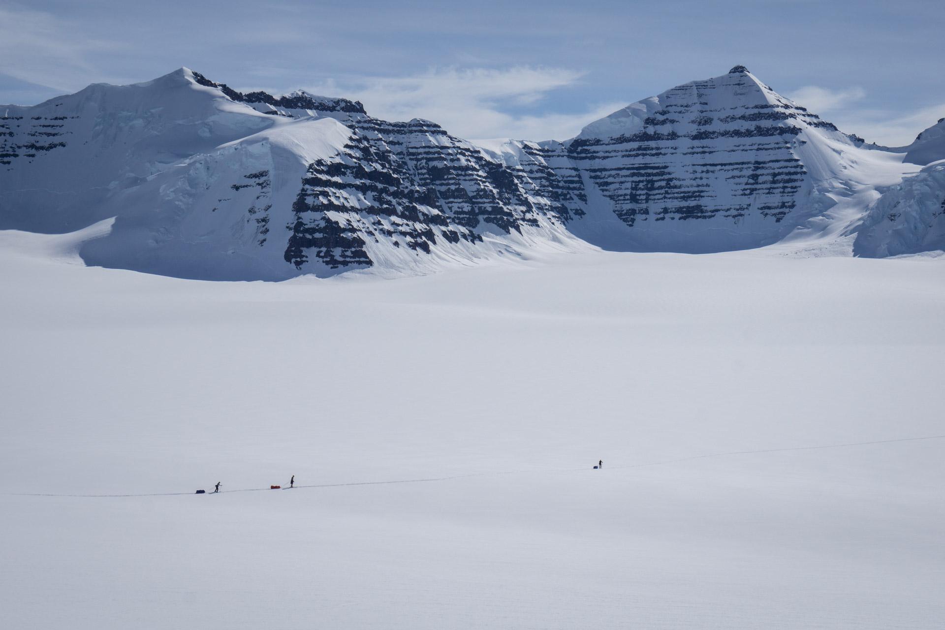 Skiers in the distance down on the flat glacier