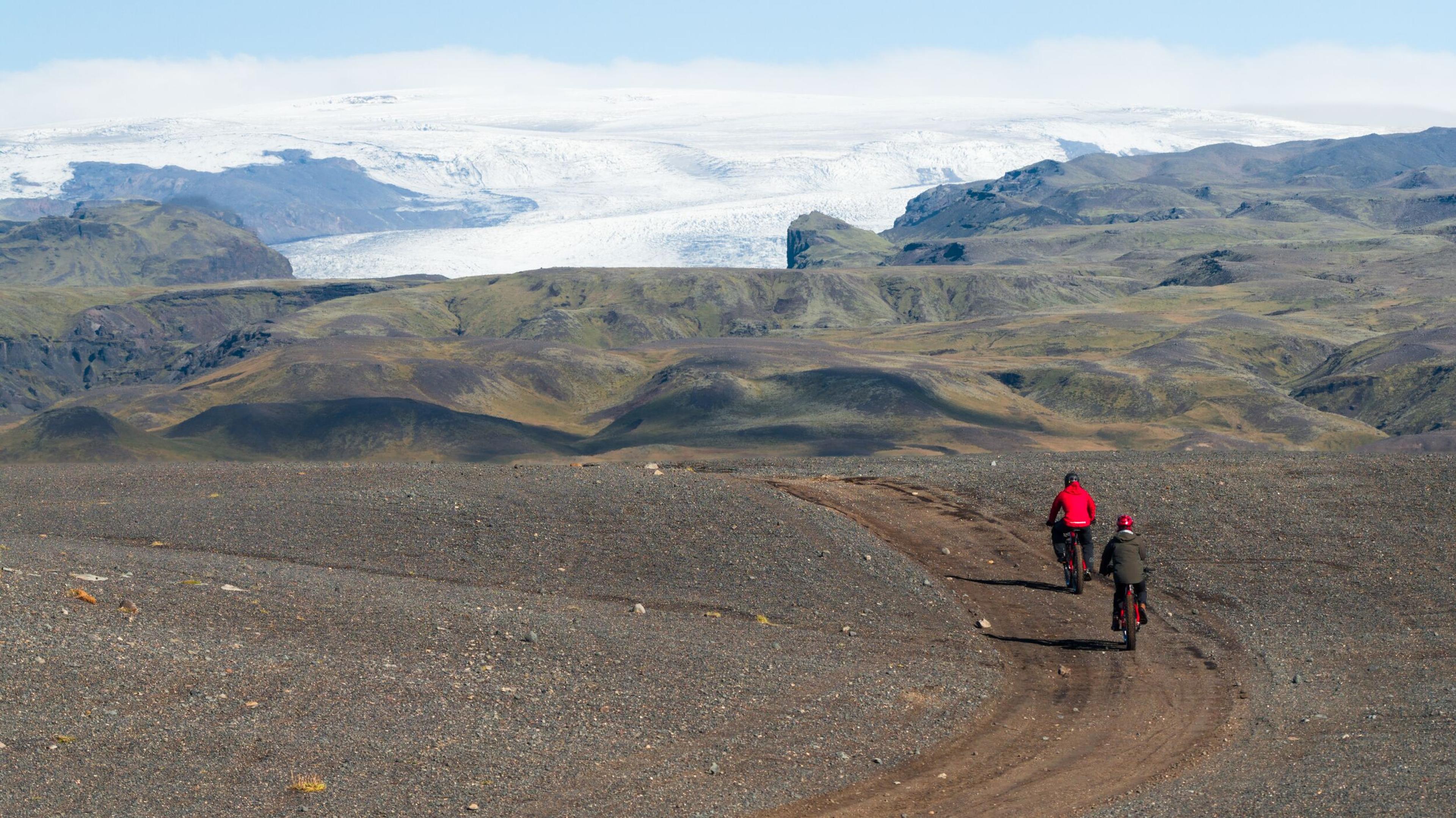 two people riding a bike with a view of a glacier in front of them