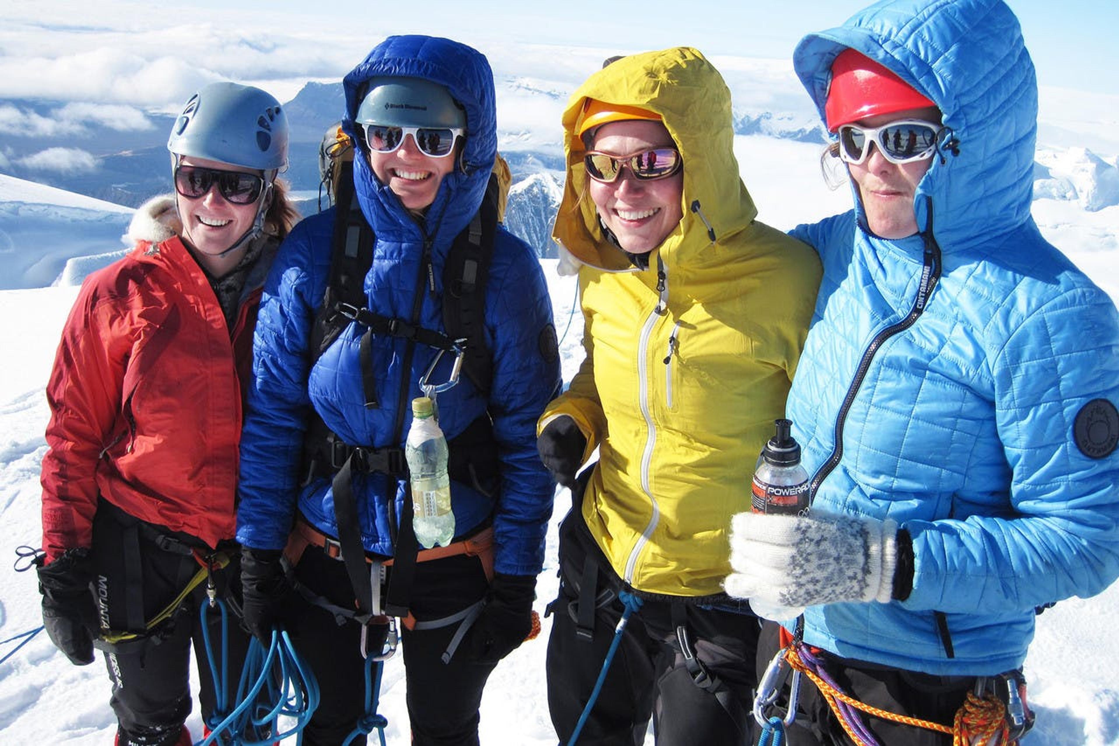 four smiling women with snowy mountains in the background