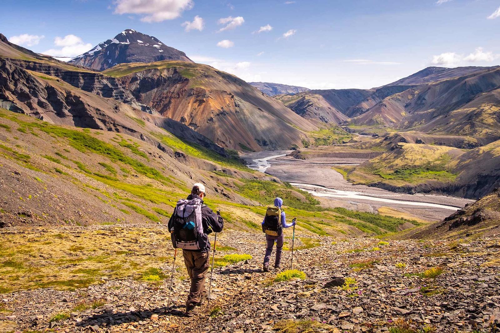 People hiking the beautiful Lonsoreafi area in Iceland with colorful mountains in the background