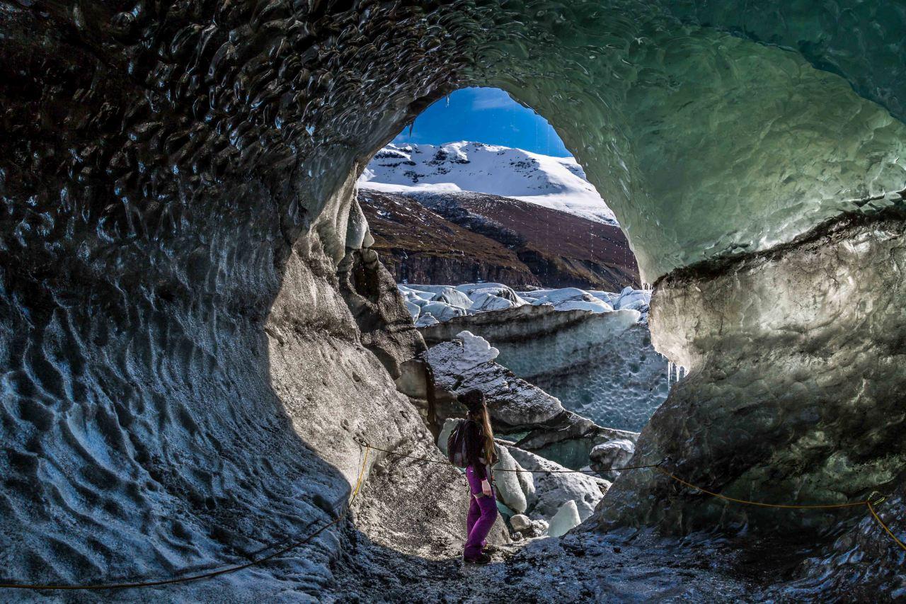 Woman standing in the entrance of an ice cave at Svínafellsjökull