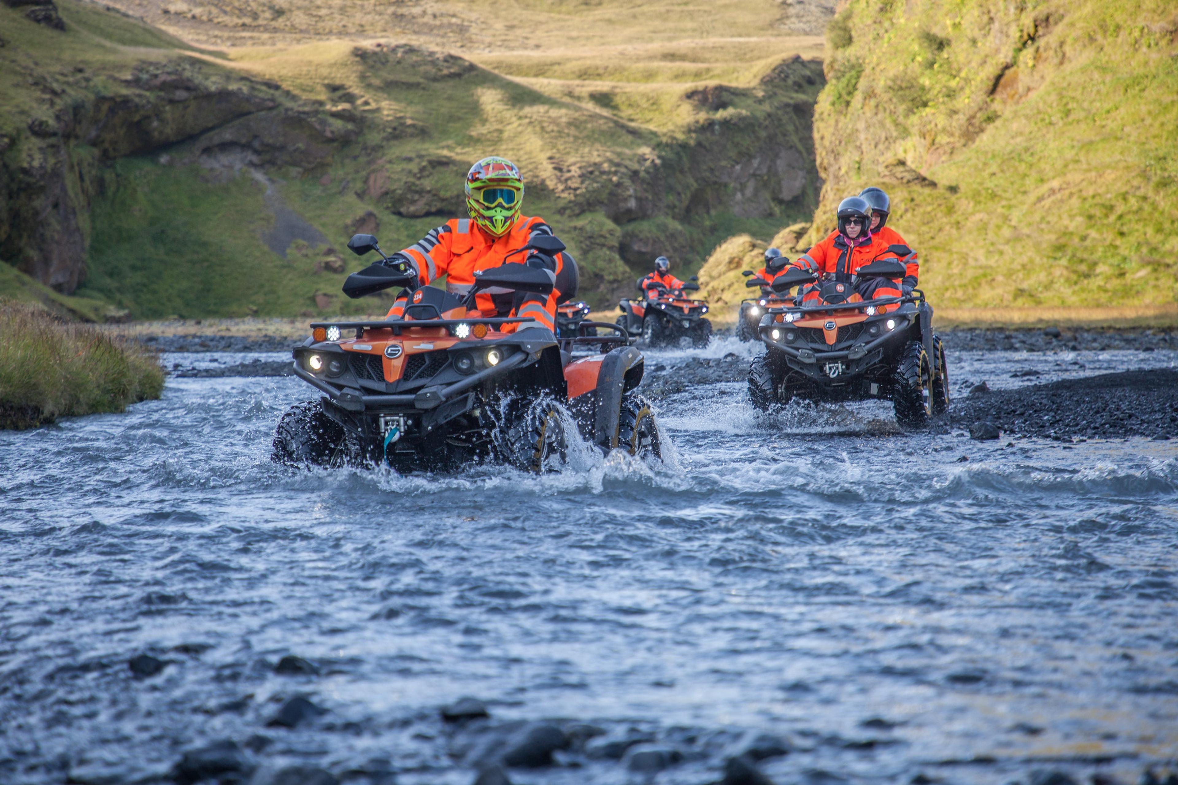 ATV quad bike drivers crossing a river in a valley