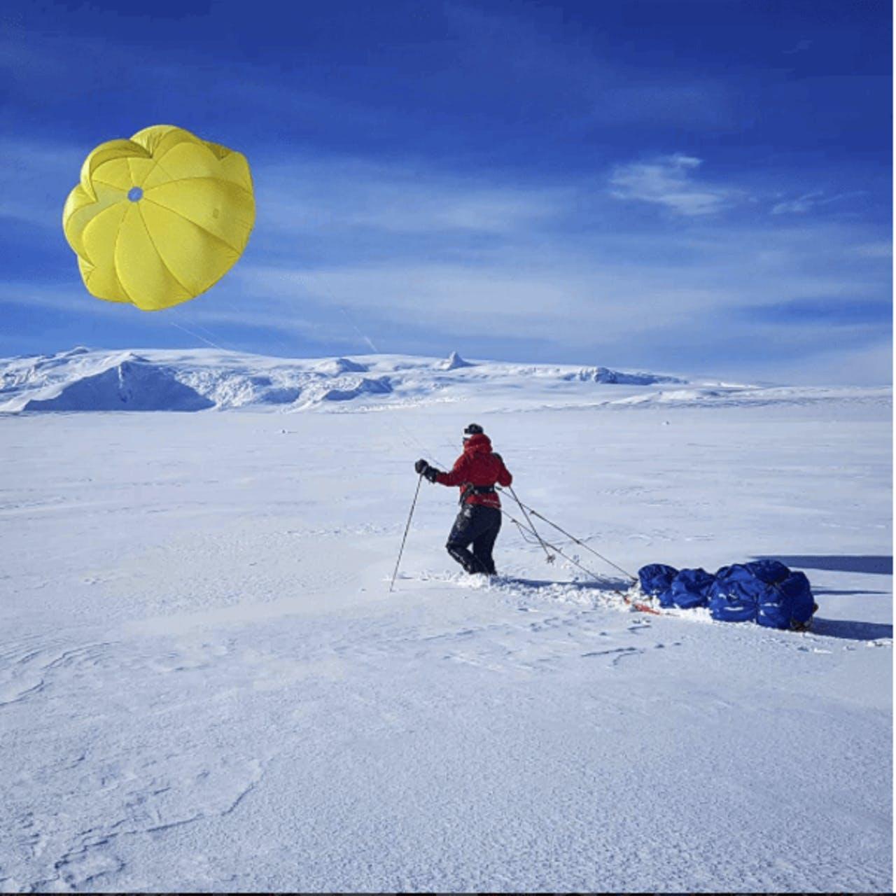 Mountaineer walking across glacier with a pulka and a kite on a course with Icelandic Mountain Guides.