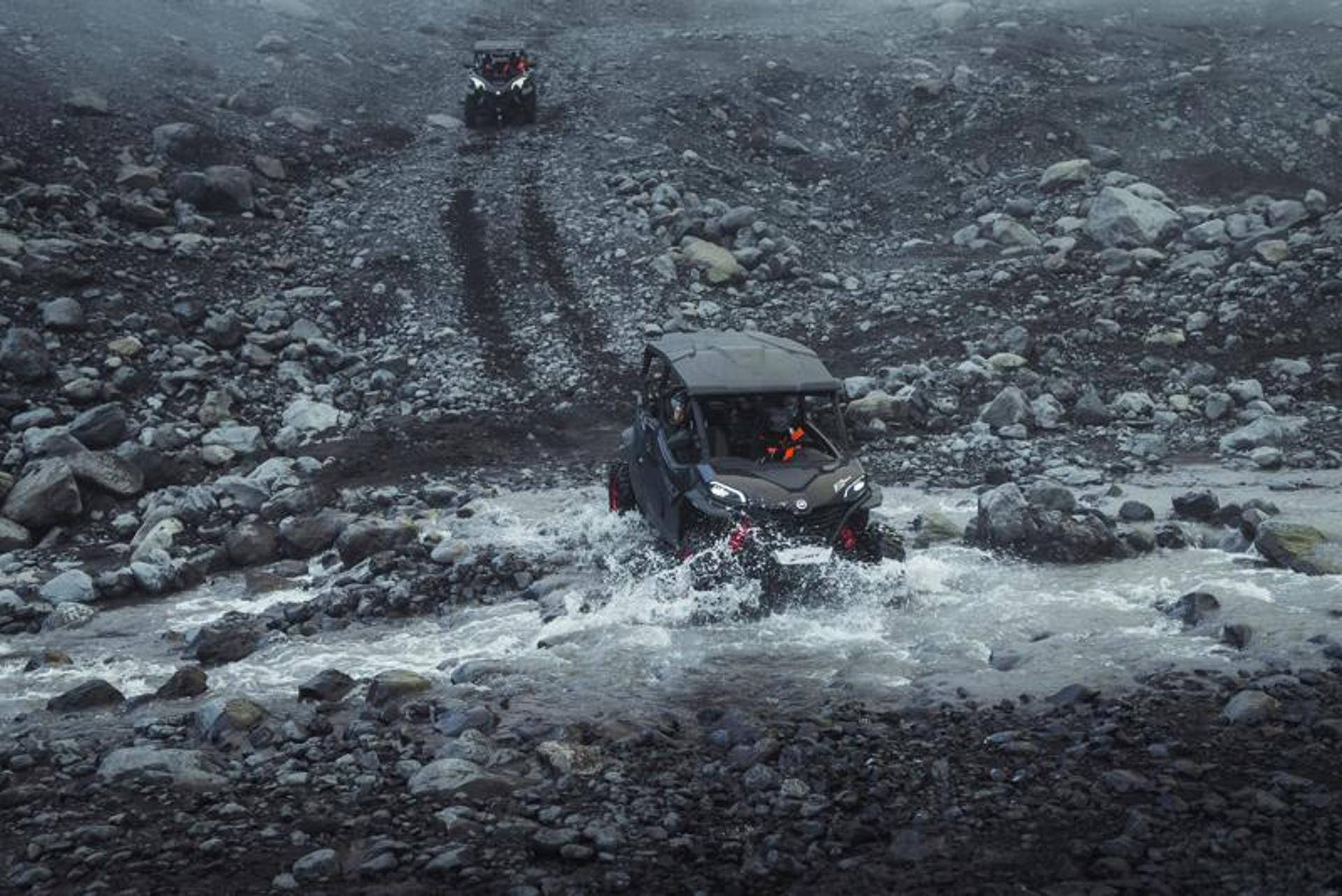 A black buggy crossing a river in the middle of black sand plains