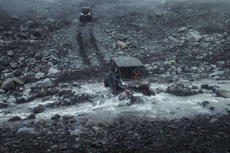 A black buggy crossing a river in the middle of black sand plains