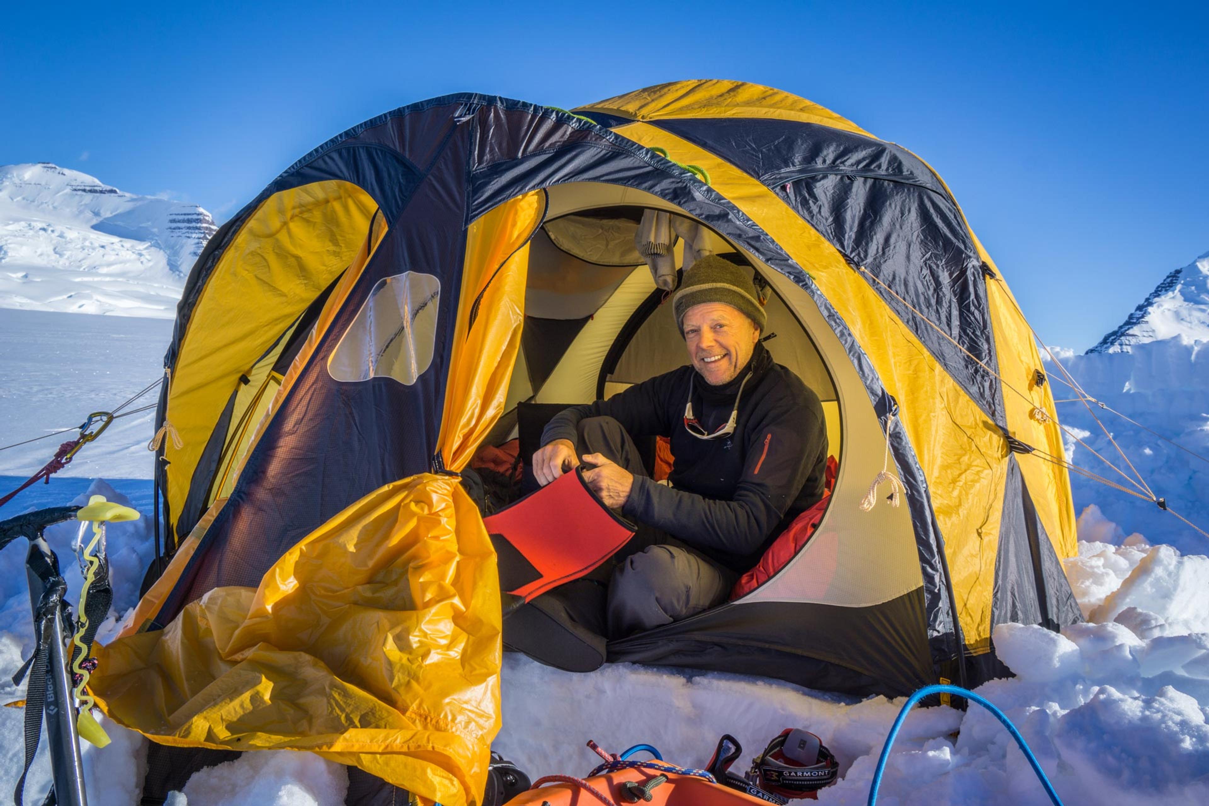 Expedition member sitting happy in the entrance of his tent