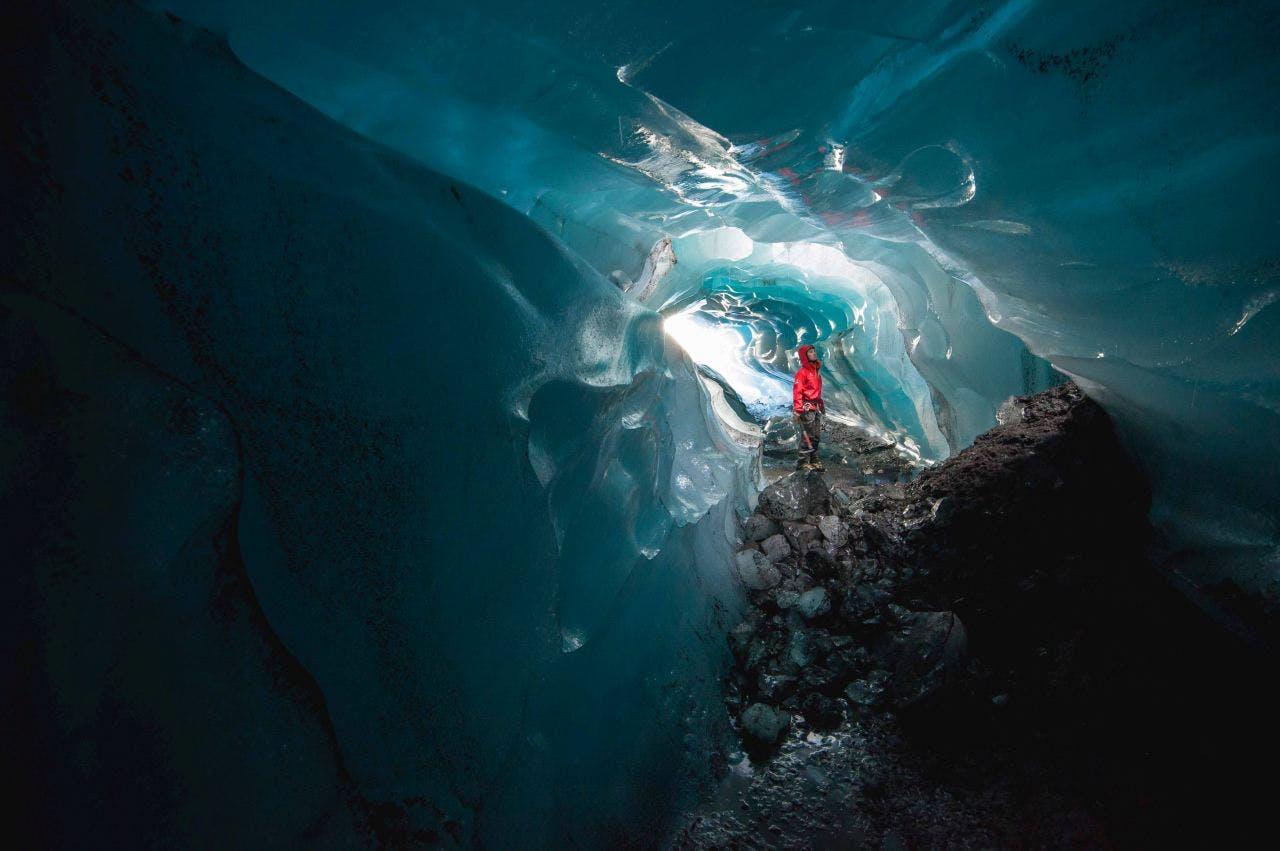 Man in a red jacket in an Ice Cave In Svínafellsjökull Glacier
