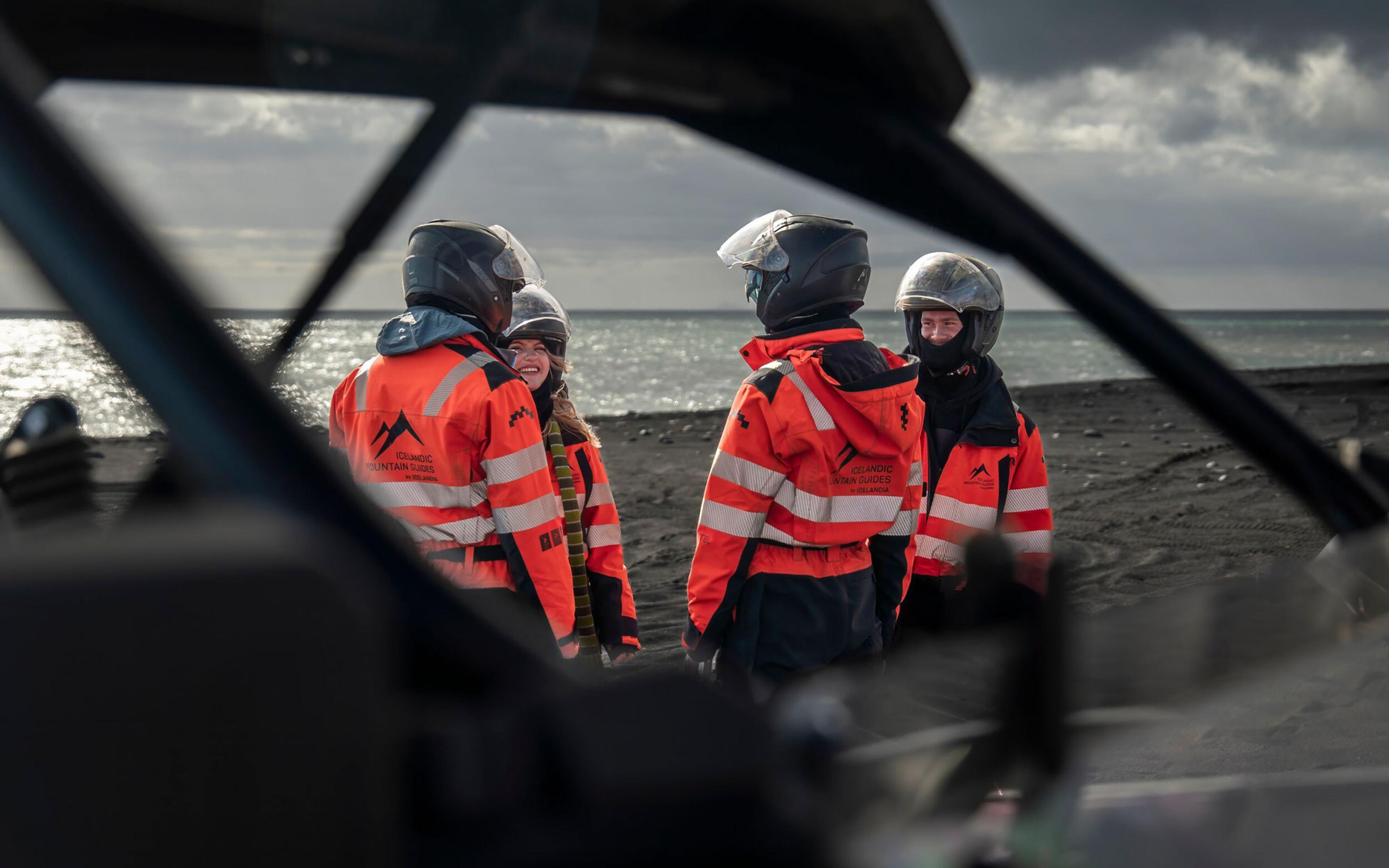 A group of buggy riders chatting near a buggy on the black sand beach in Iceland