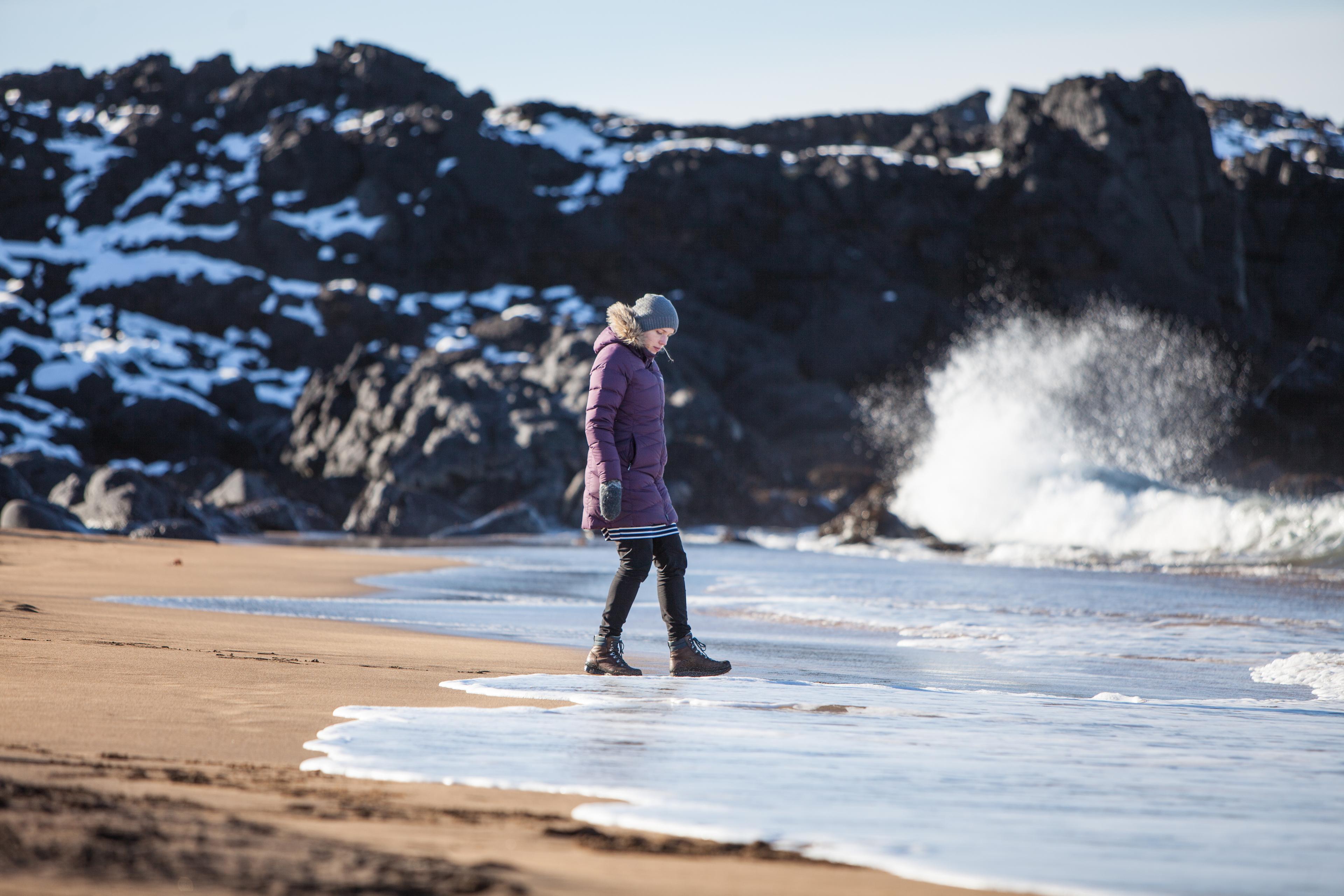 A girl standing on a white sand beach in Snaefellsnes