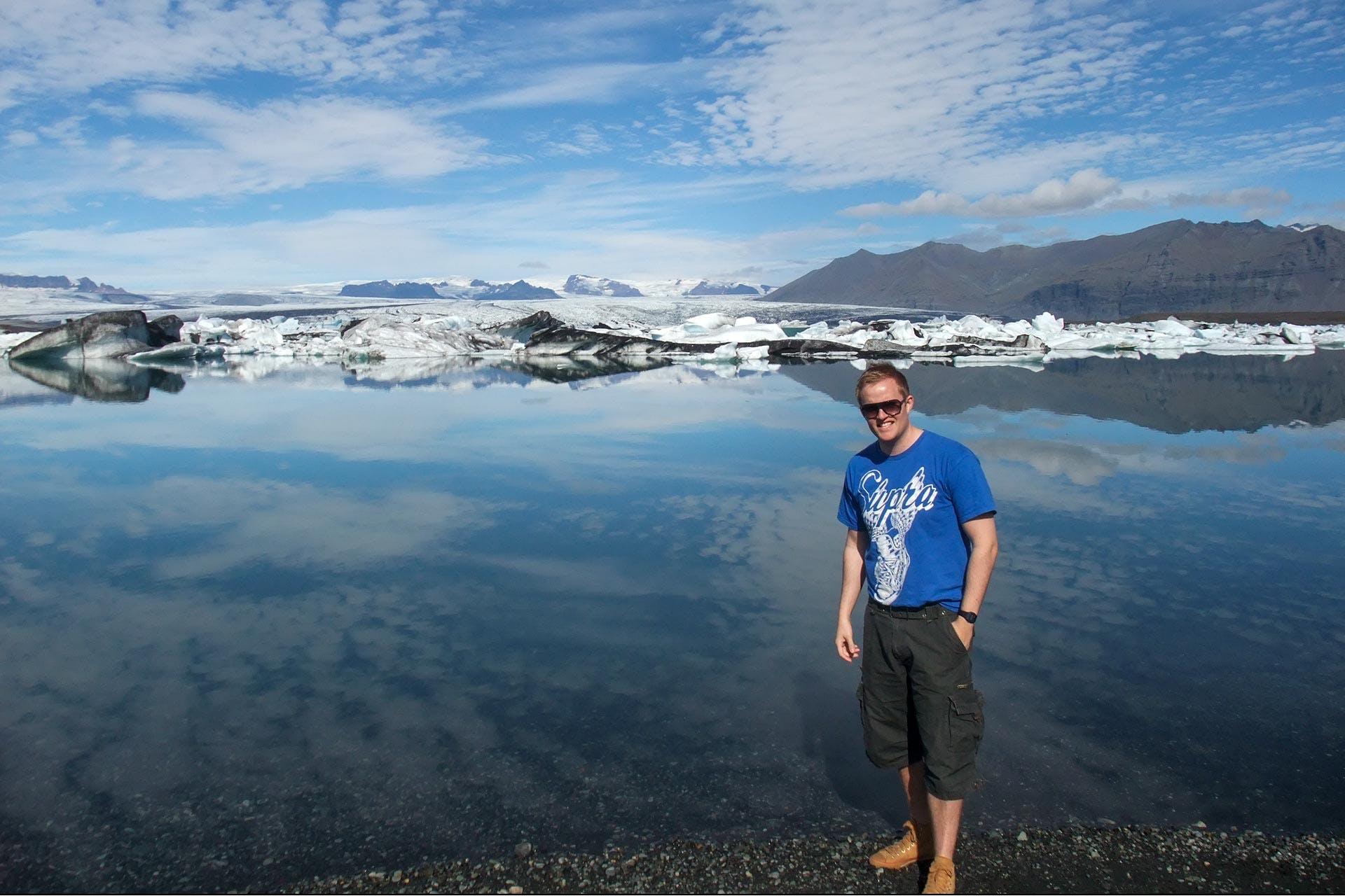 A smiling man in shorts and t-shirt at the Glacier Lagoon in Iceland