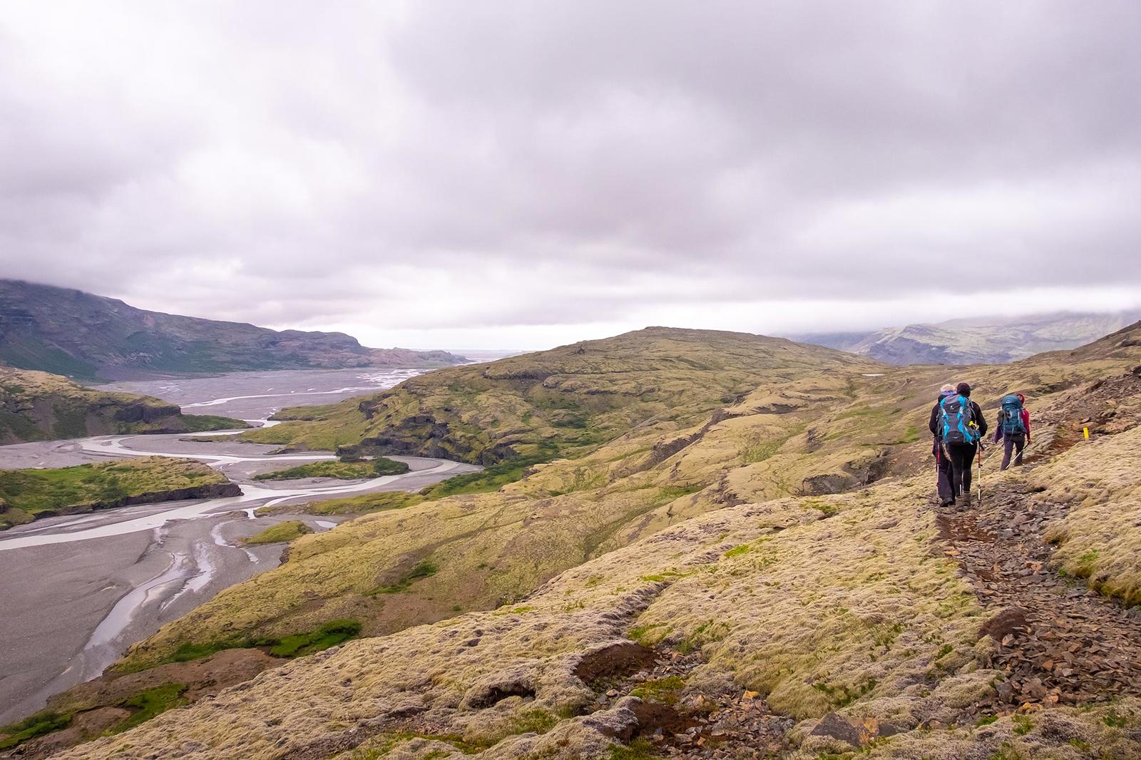 Hikers walking towards the lowlands where the river is spreading out on the sands