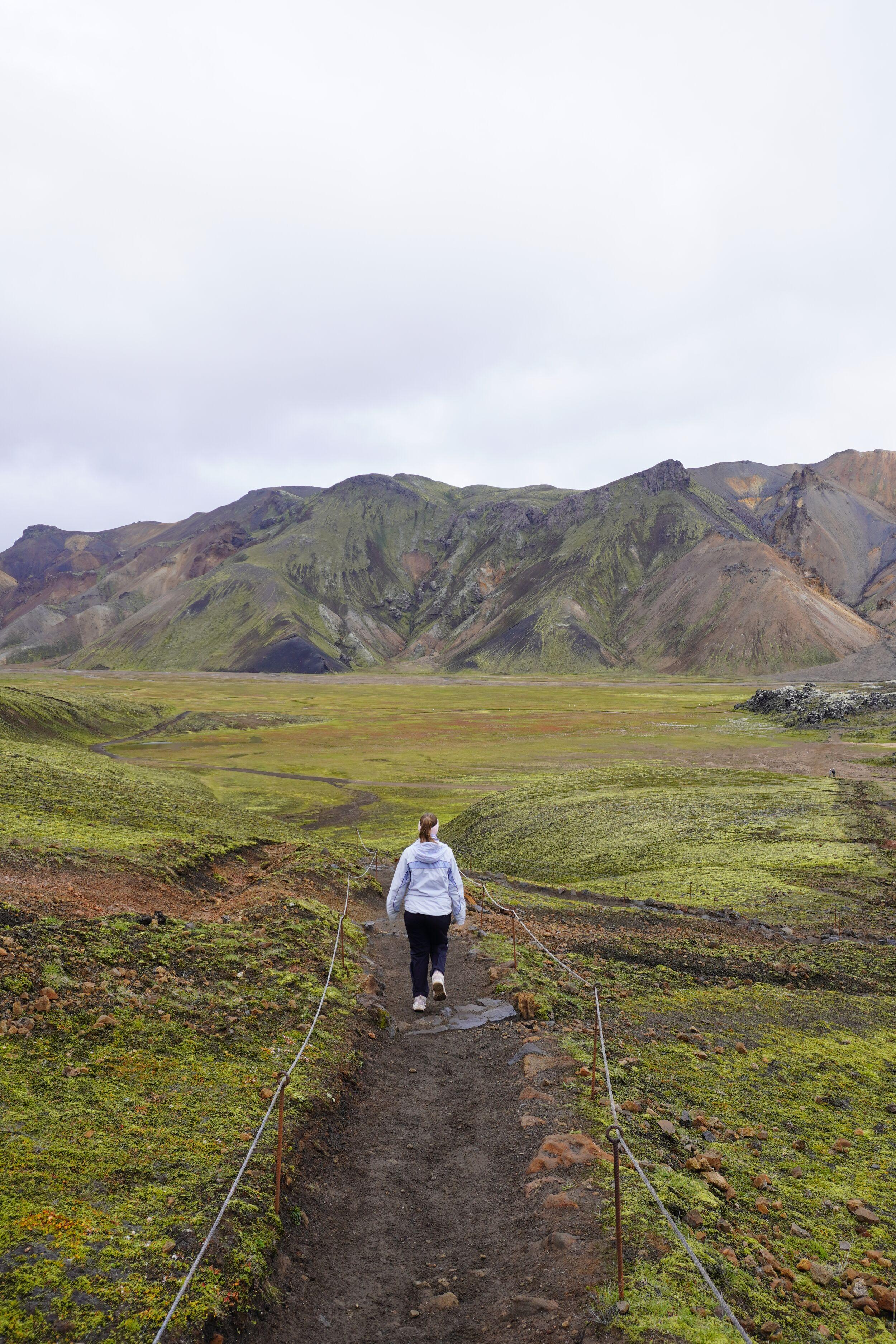 A person hiking on a marked trail in green and colorful landscapes in Iceland