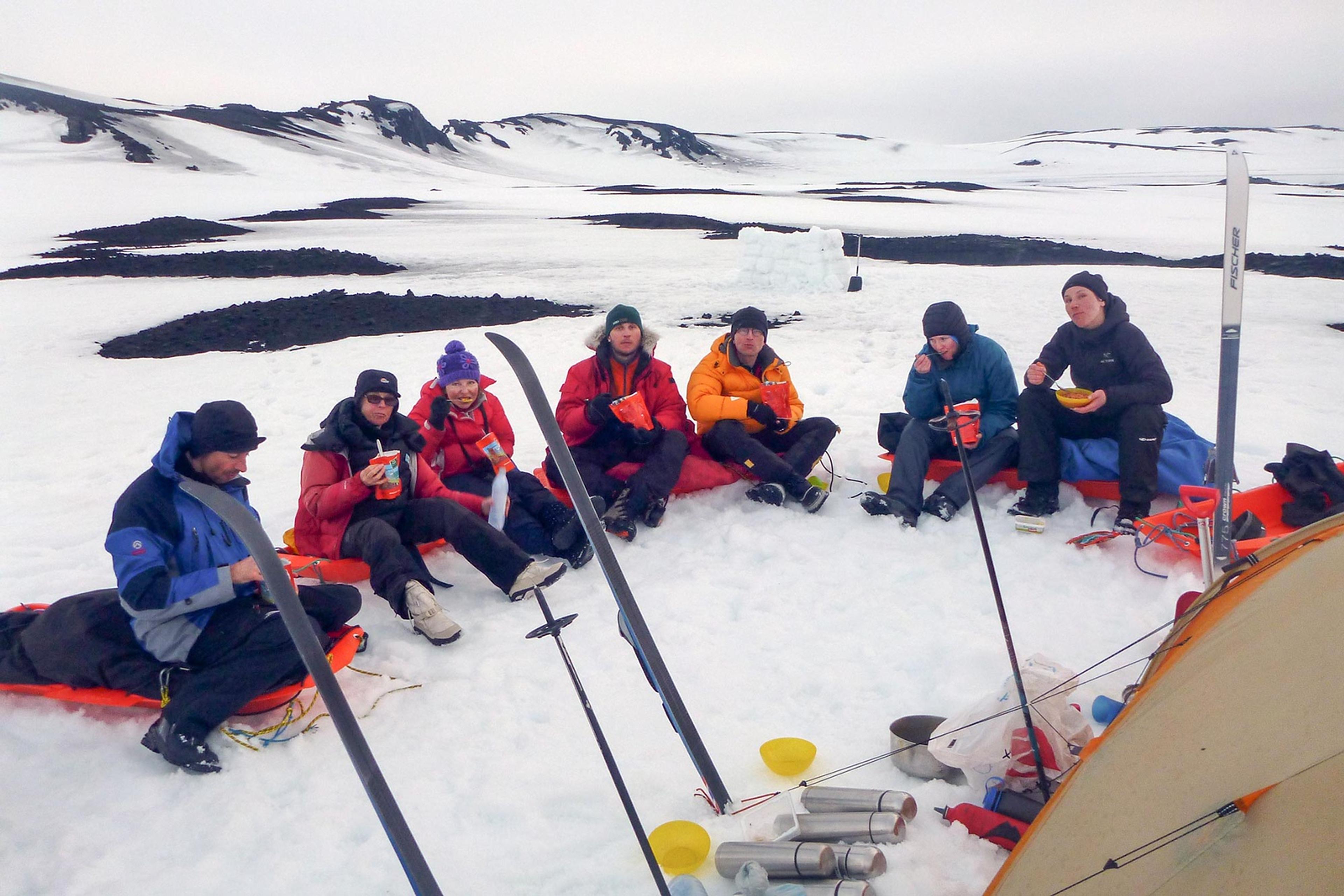 Skiers having a breakfast sitting in a half round by a tent