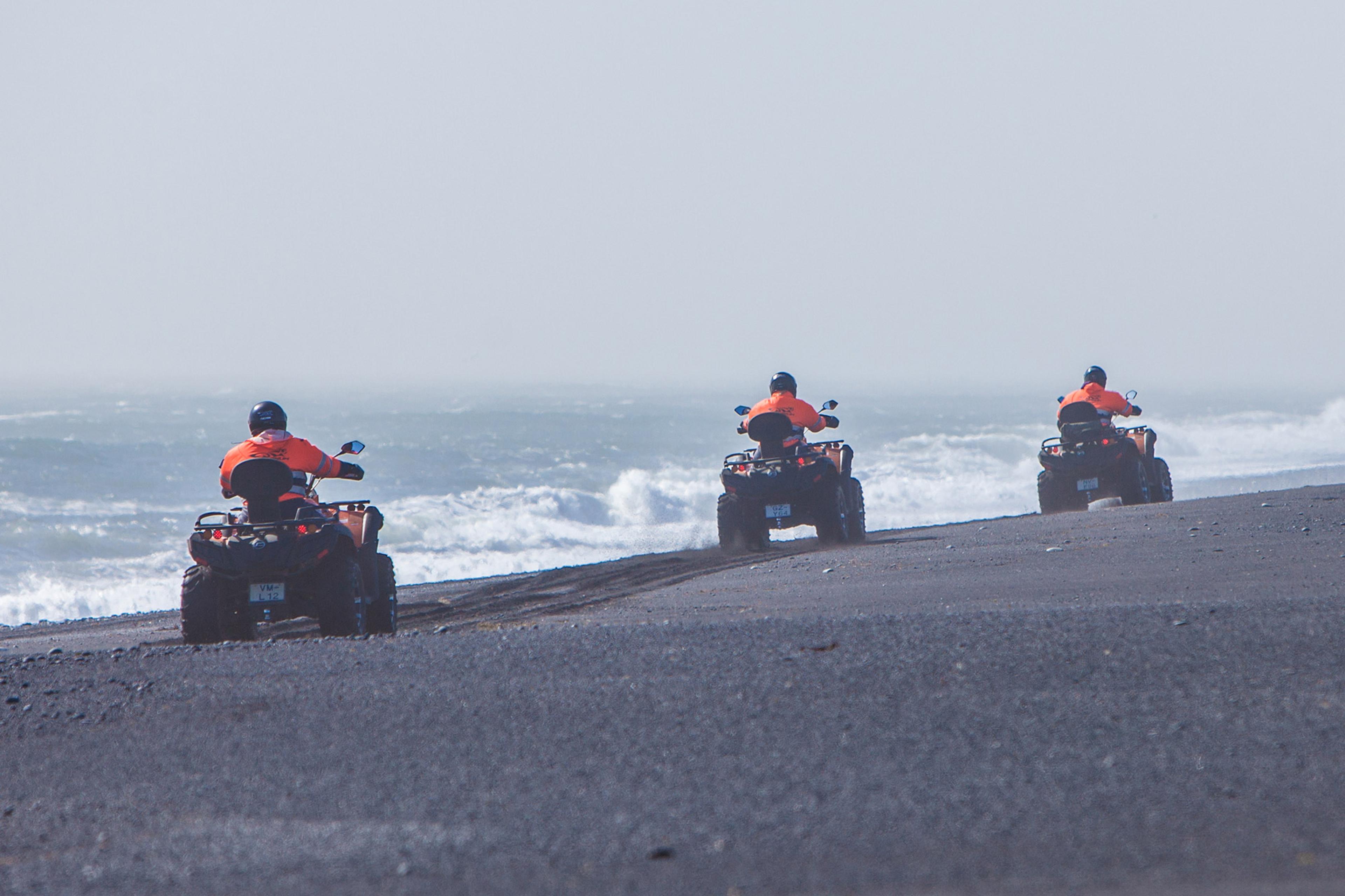 ATV quad bike riders going wild on the black sand bach with the raging Atlantic ocean close by