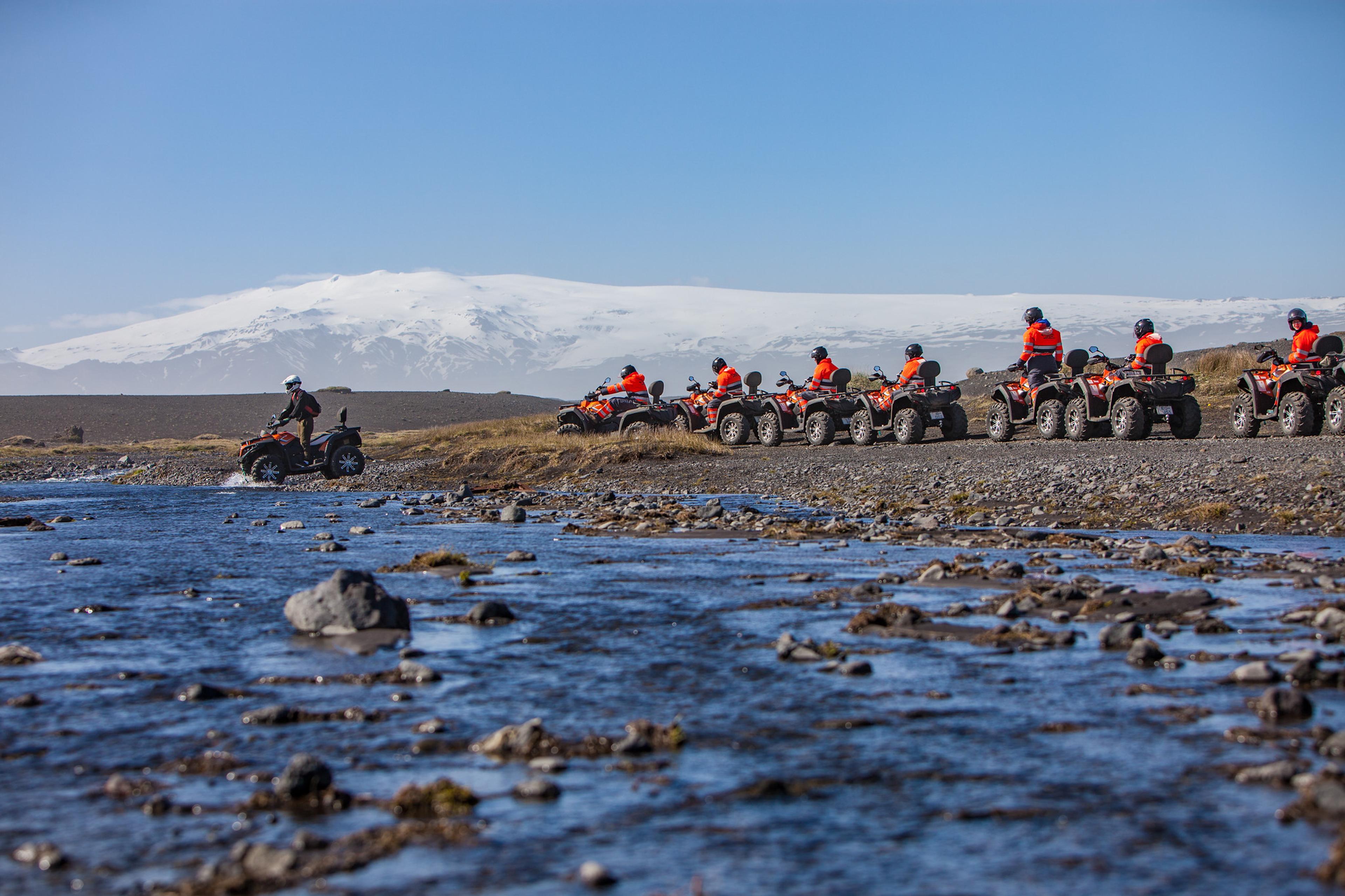 ATV bikes crossing a river with Eyjafjallajökull glacier in the background