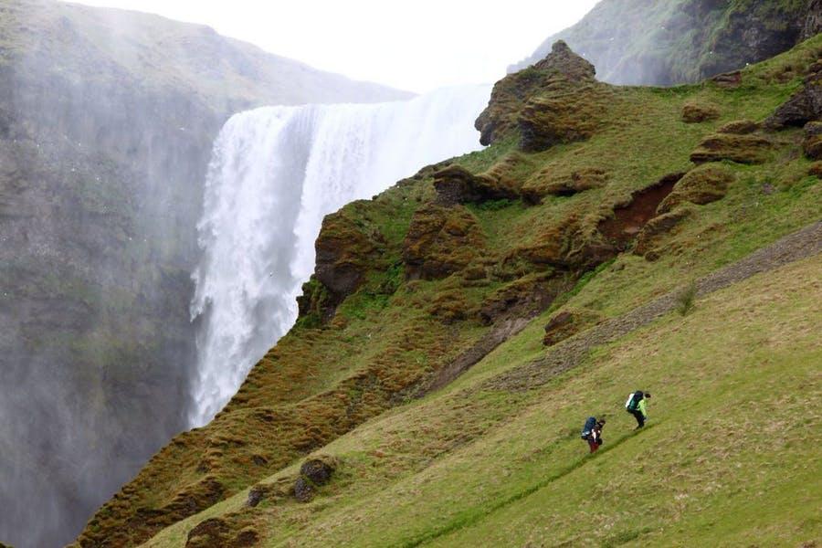 Two people hiking next to a big waterfall