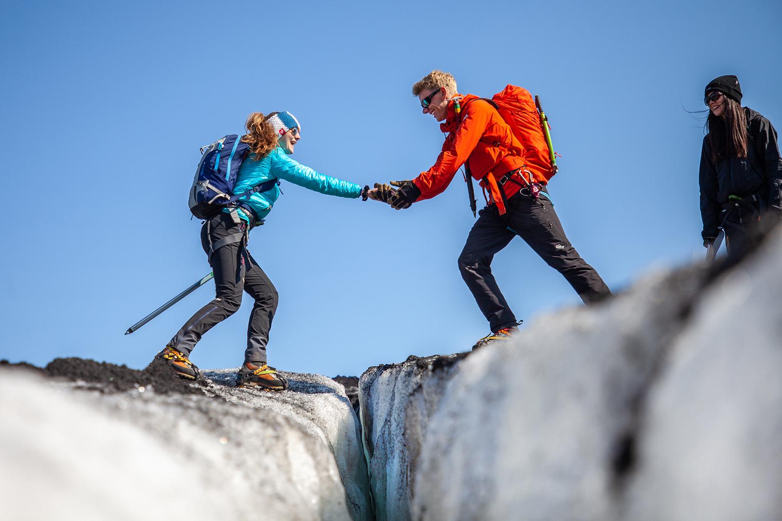 The guide helping a girl stepping over a small crevasse