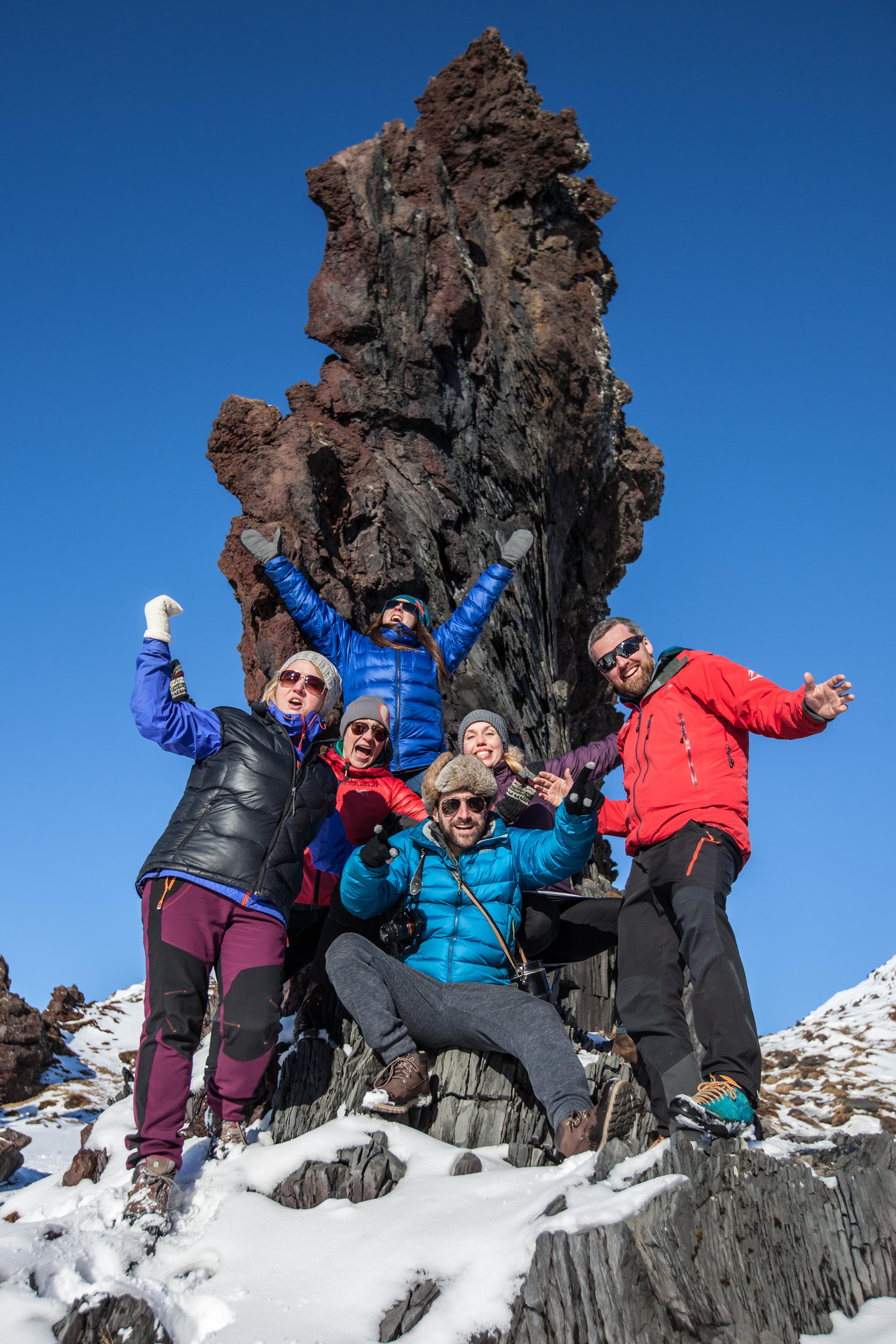 Happy people posing in front of a lava rock formation