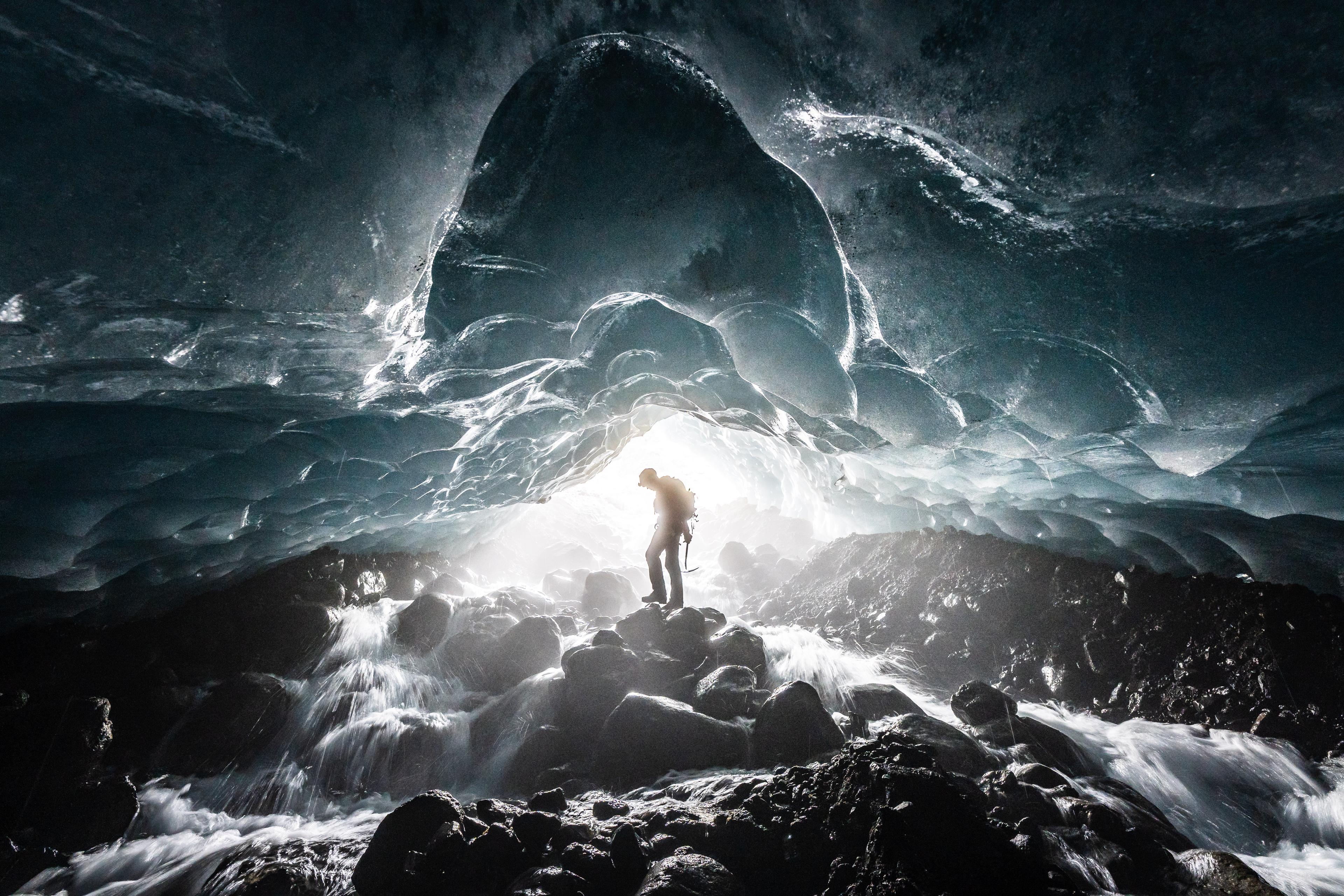 Silhouette of a glacier guide exploring an ice cave