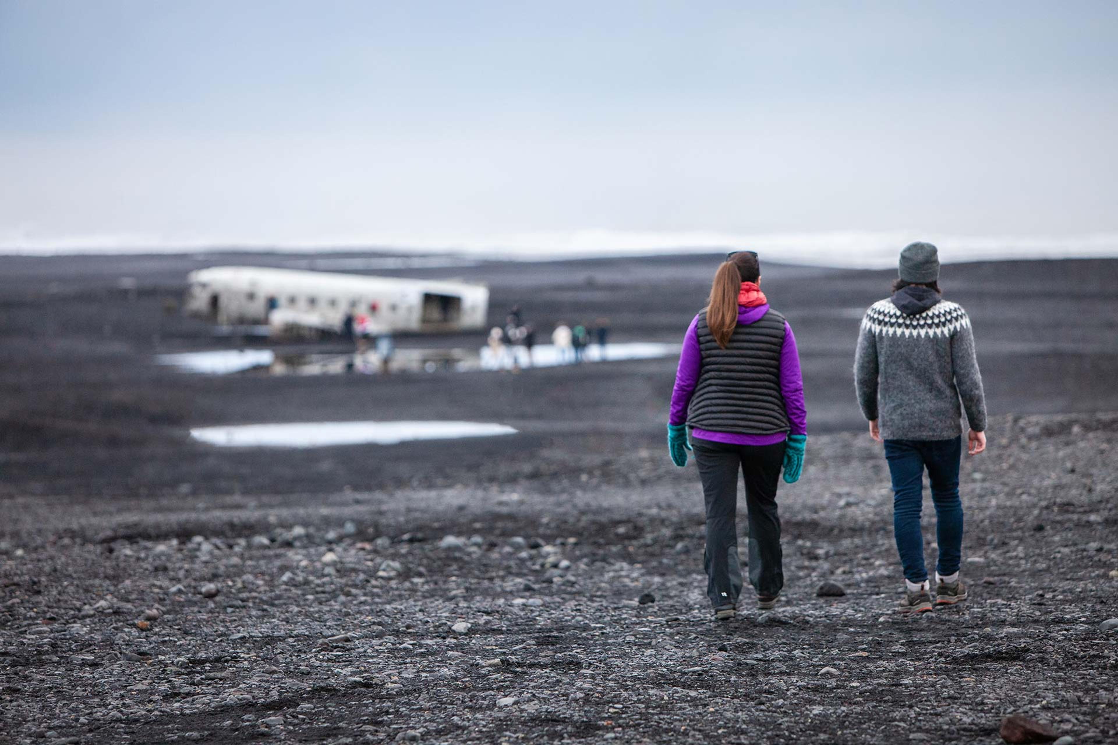 walking towards a plane wreck on black sand