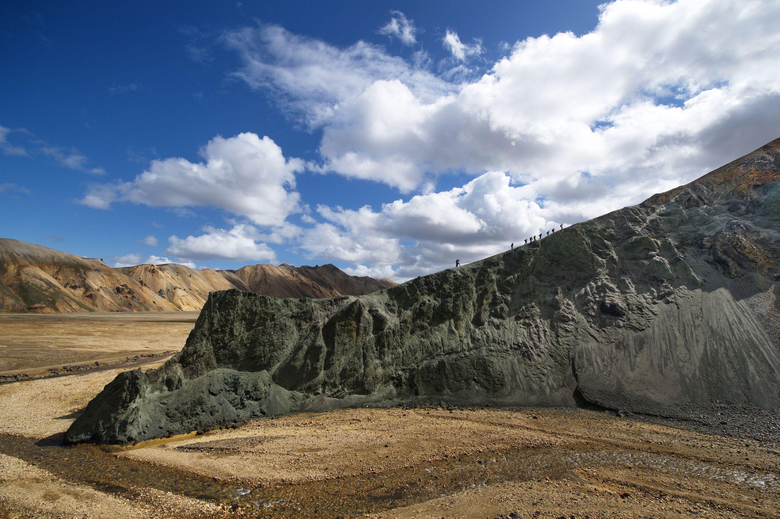 Hikers in the distance ascending a ridge in the colourful landscapes of Landm