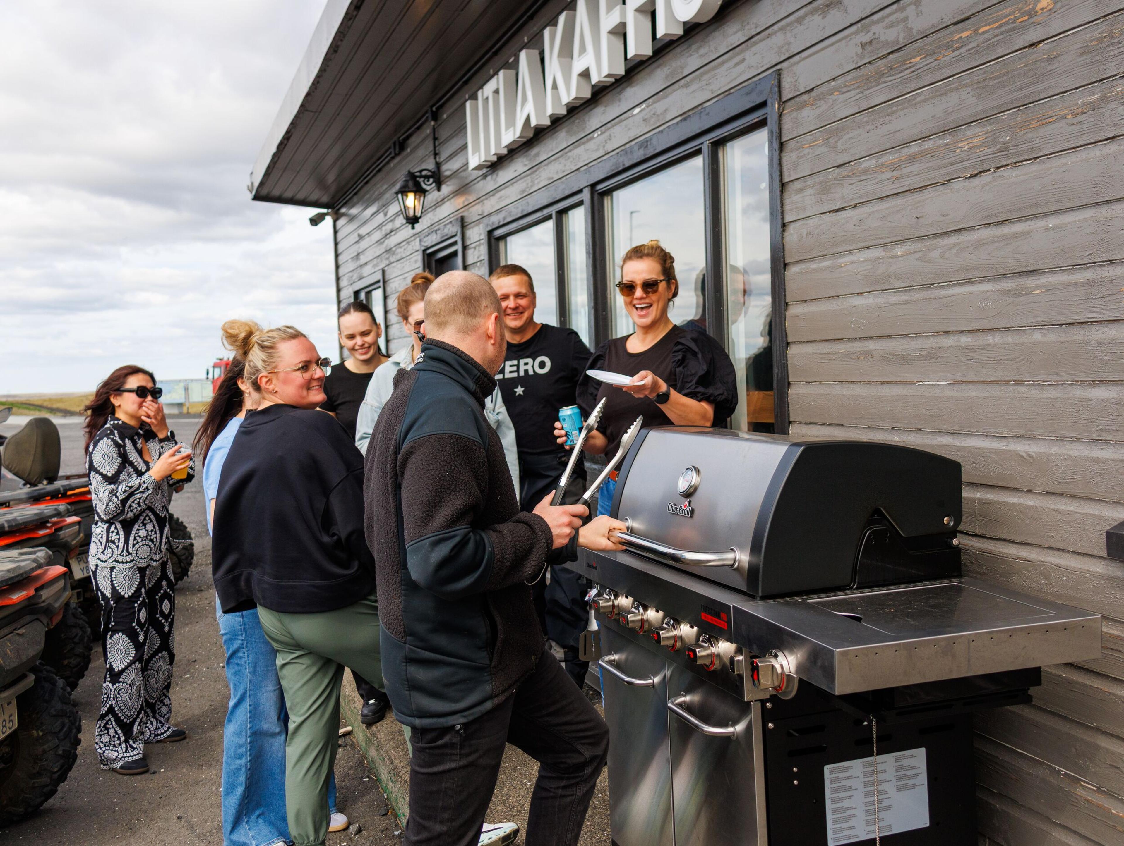 People gathered around a grill in front of Litla Kaffistofan.