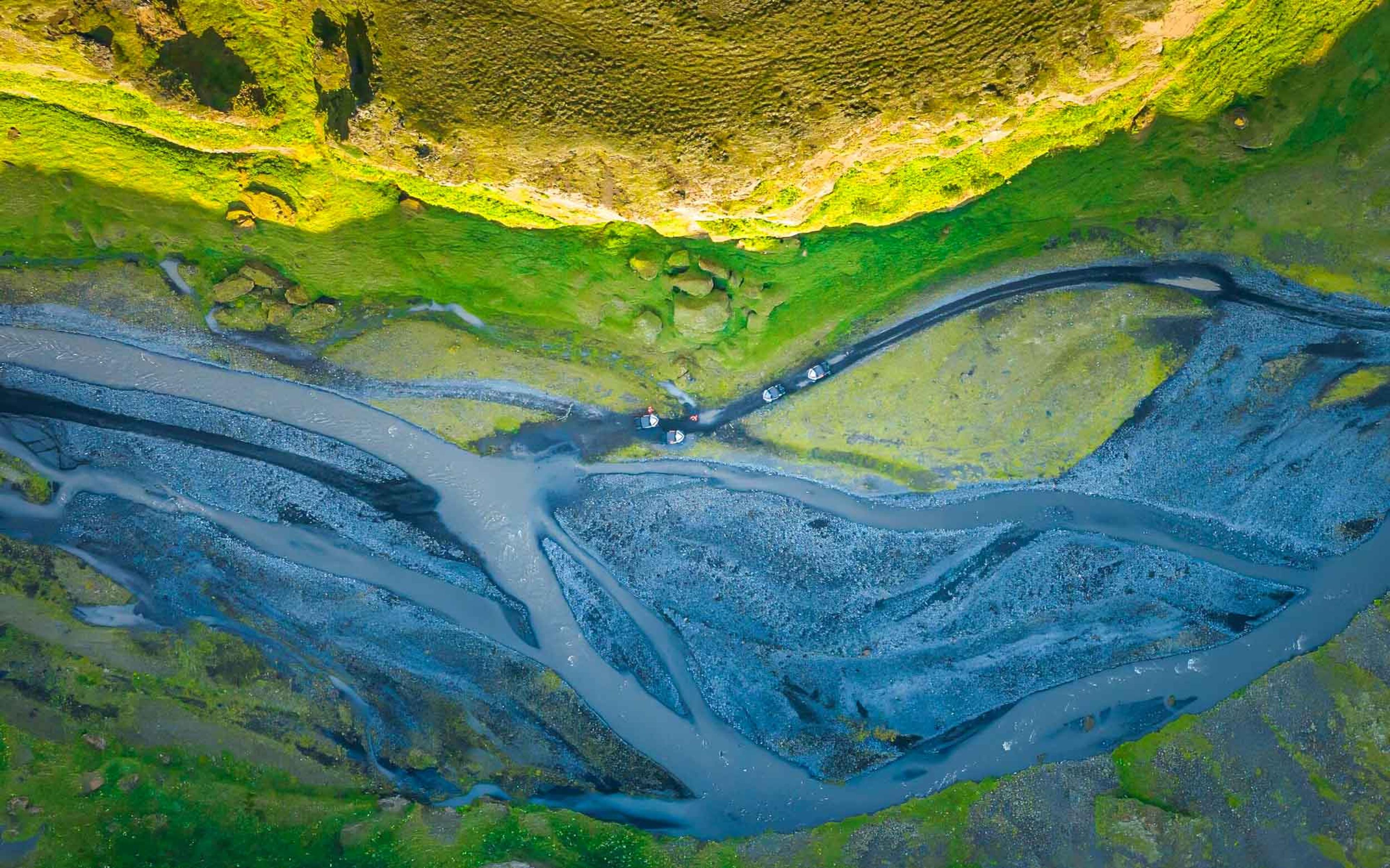 Buggies seen from above driving through a river bed 