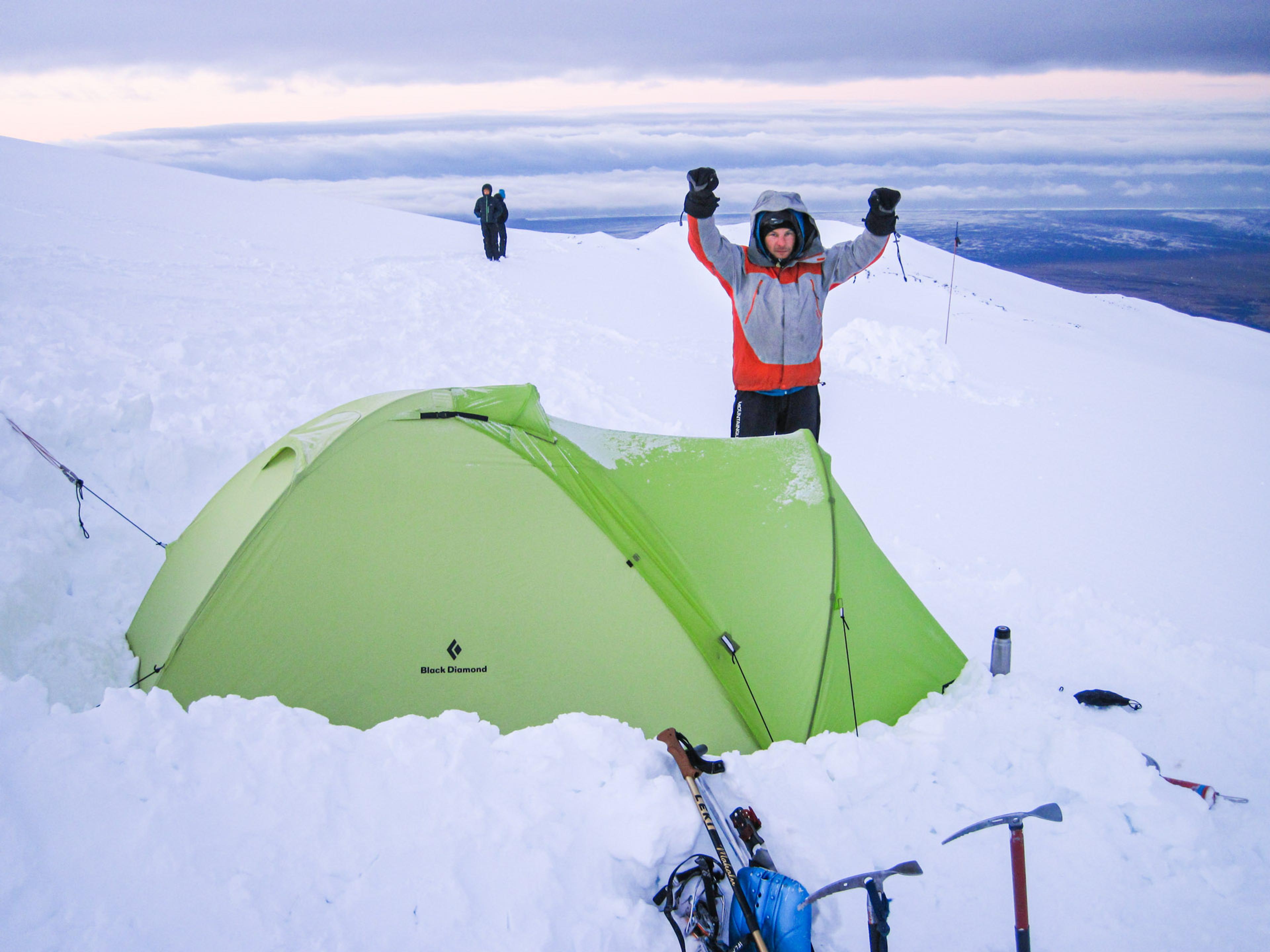 man with a tent on a snowy mountain in the morning