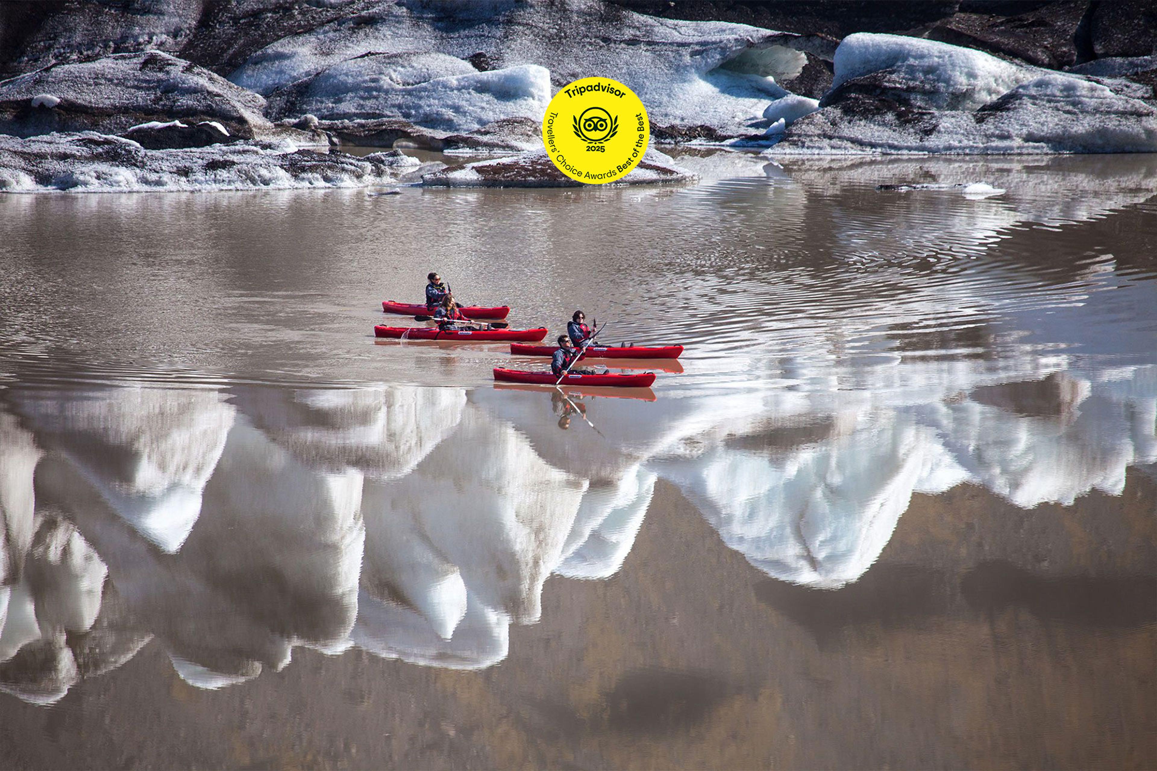 A man on a red kayak paddling through some ice bergs.