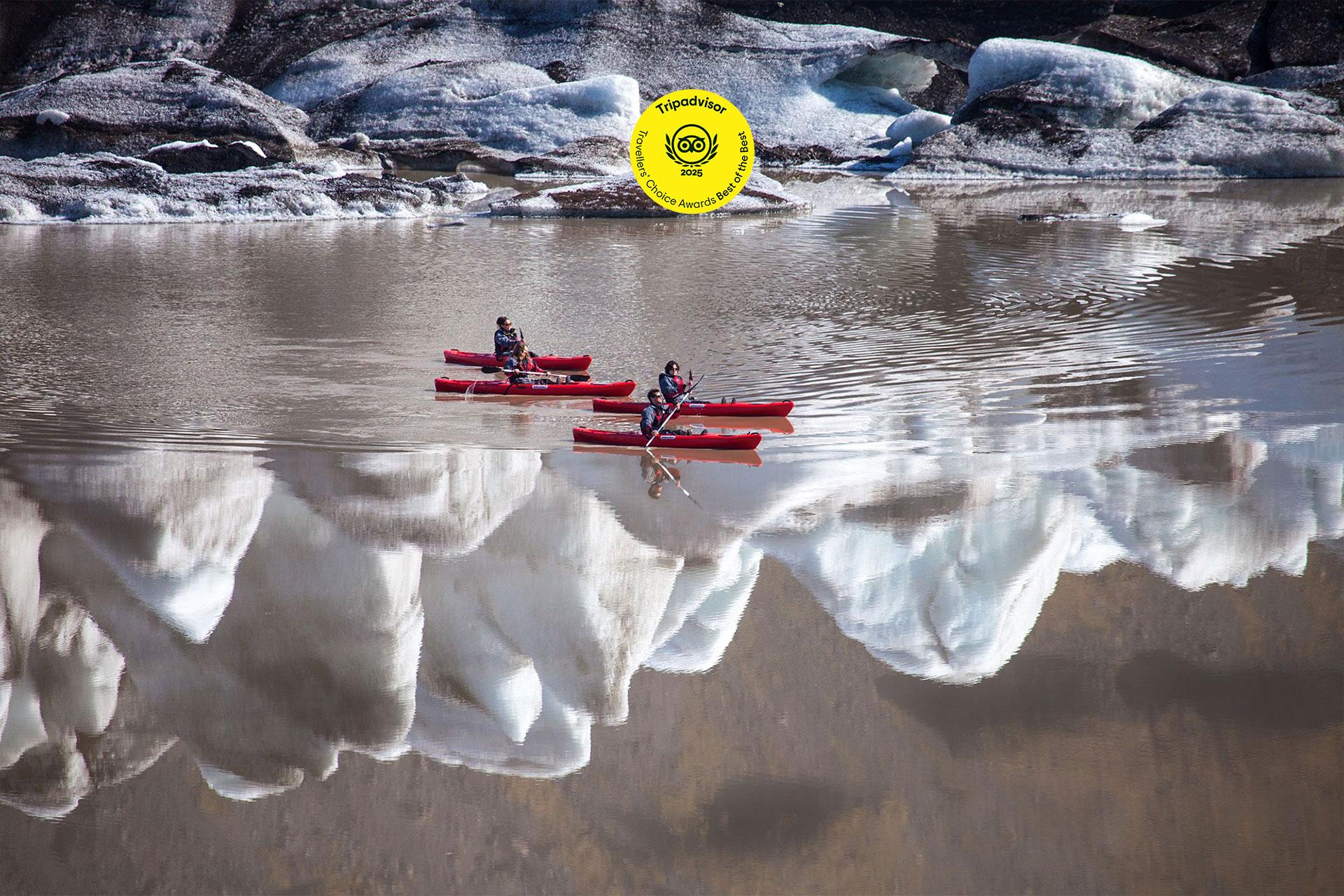 A man on a red kayak paddling through some ice bergs.